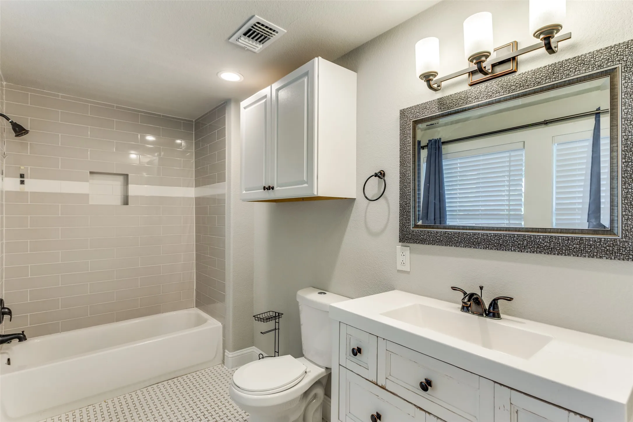 White vanity with integrated sink, bronze-finish faucet, and coordinating framed mirror