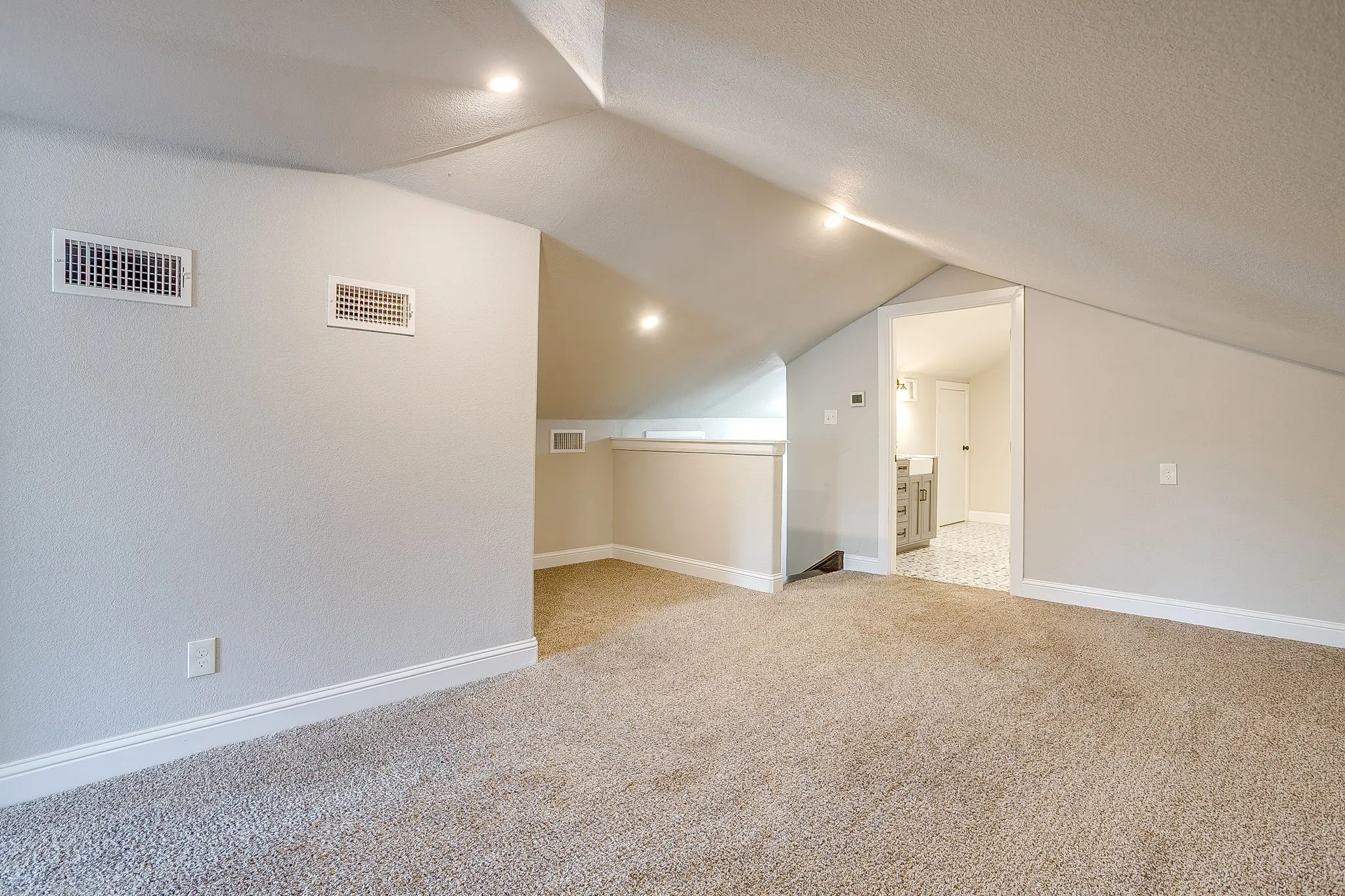 Carpeted area with sloped ceilings, recessed lighting, and white baseboards