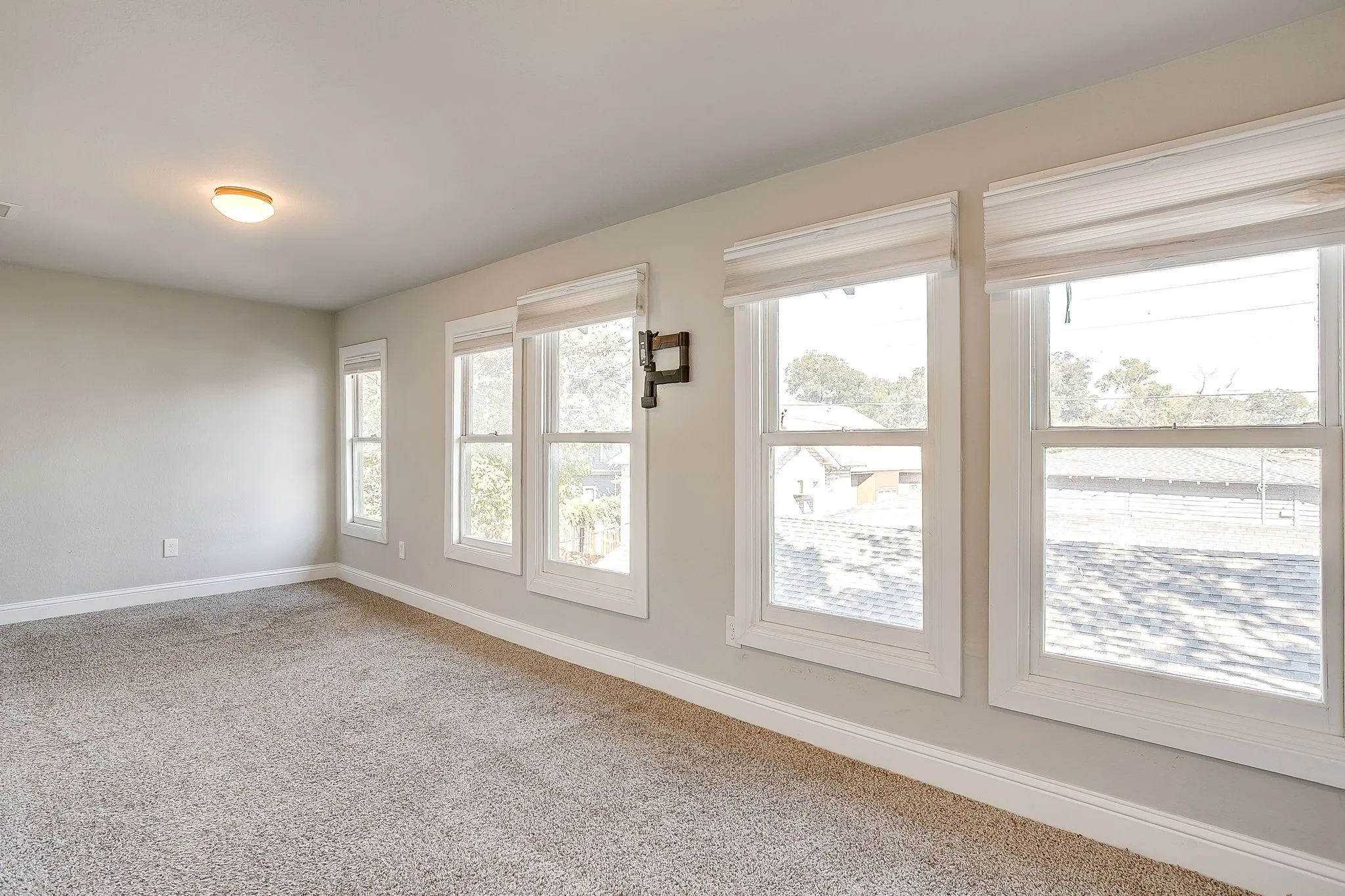 Neutral paint palette, textured carpeting, multiple double-hung windows, window treatments, and a ceiling-mounted light fixture