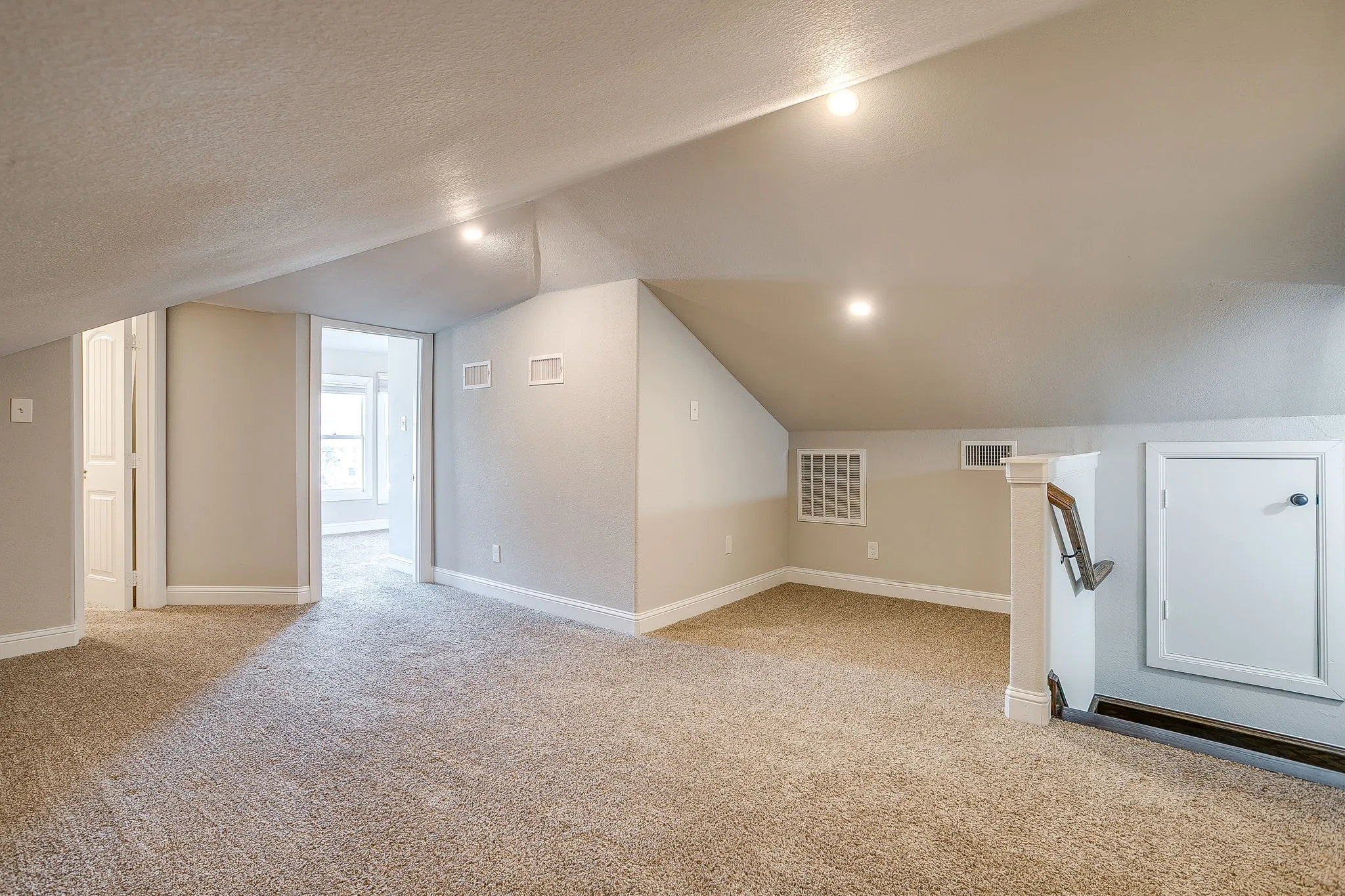Carpeted room with sloped ceilings, recessed lighting, and white trim