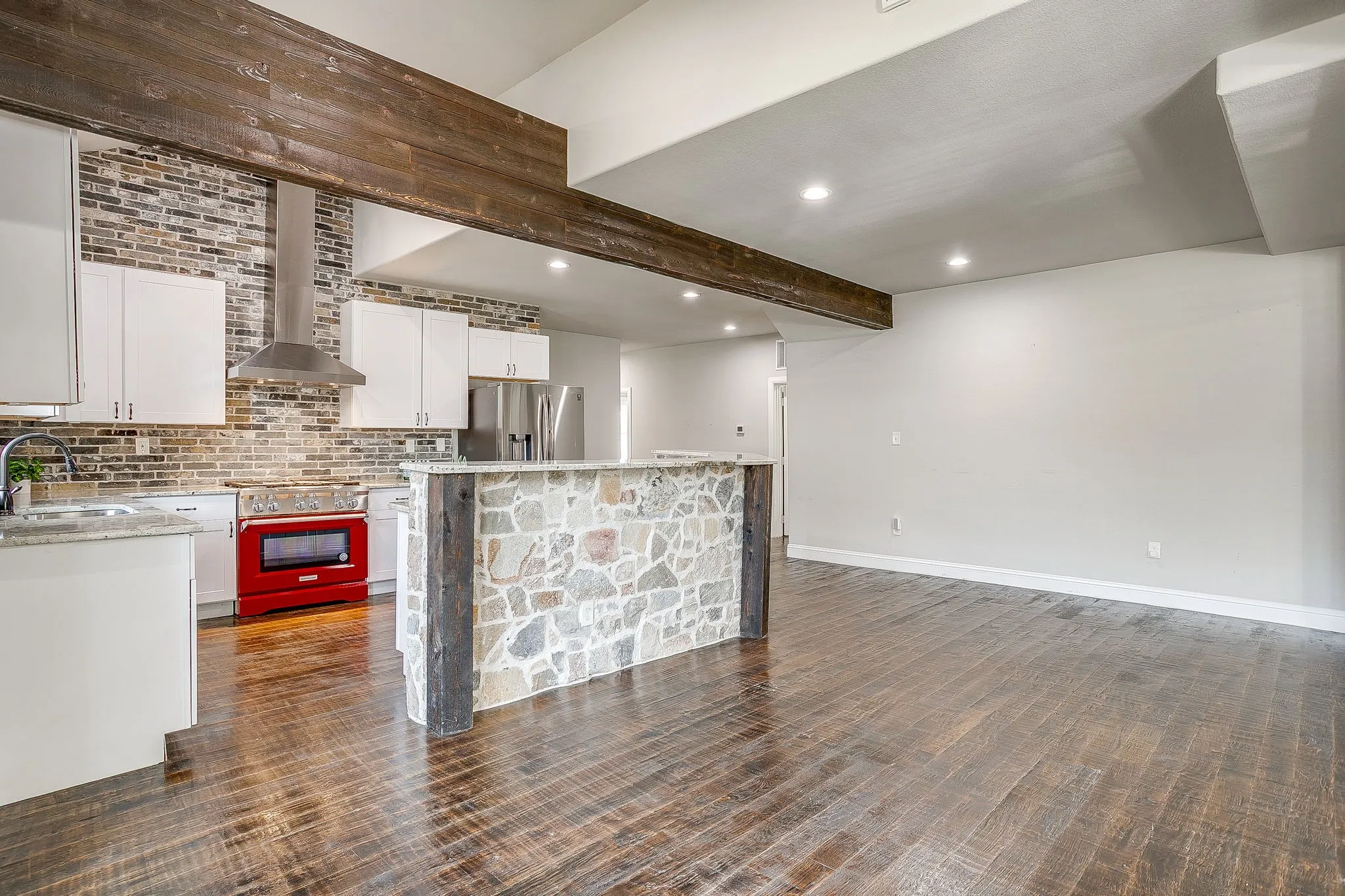 Open-concept kitchen and living area featuring wood-finish flooring, recessed lighting, and a stone-faced island