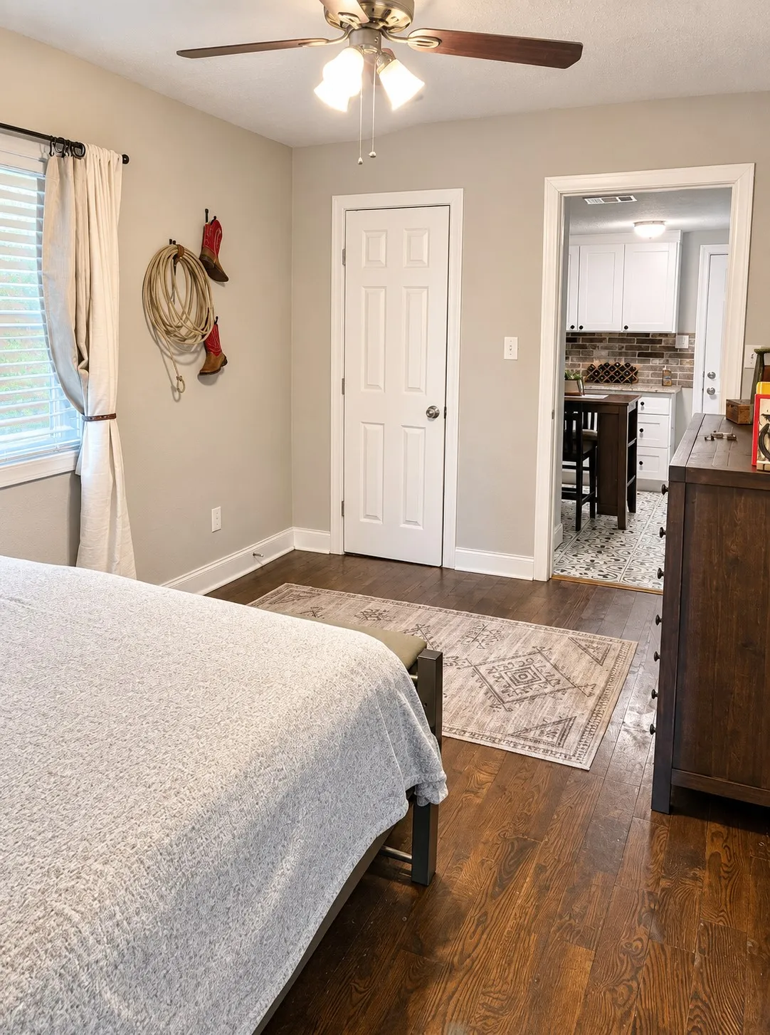 Wood-finish flooring, ceiling fan with integrated lighting, white paneled door, and neutral wall tones