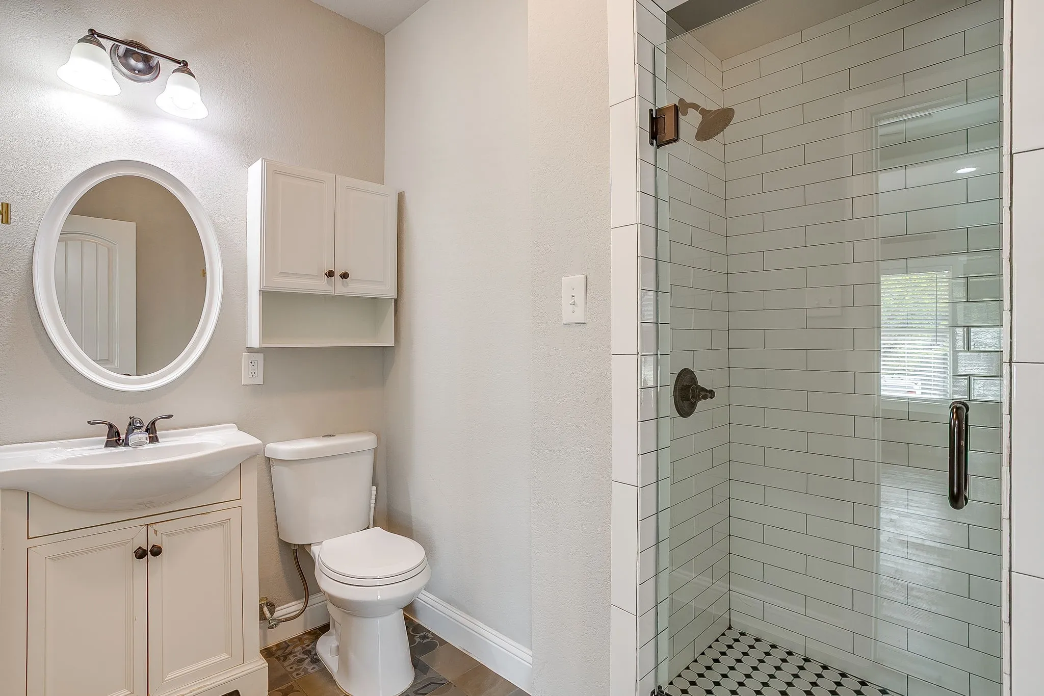 White vanity with an integrated sink, oval mirror, and overhead sconce lighting