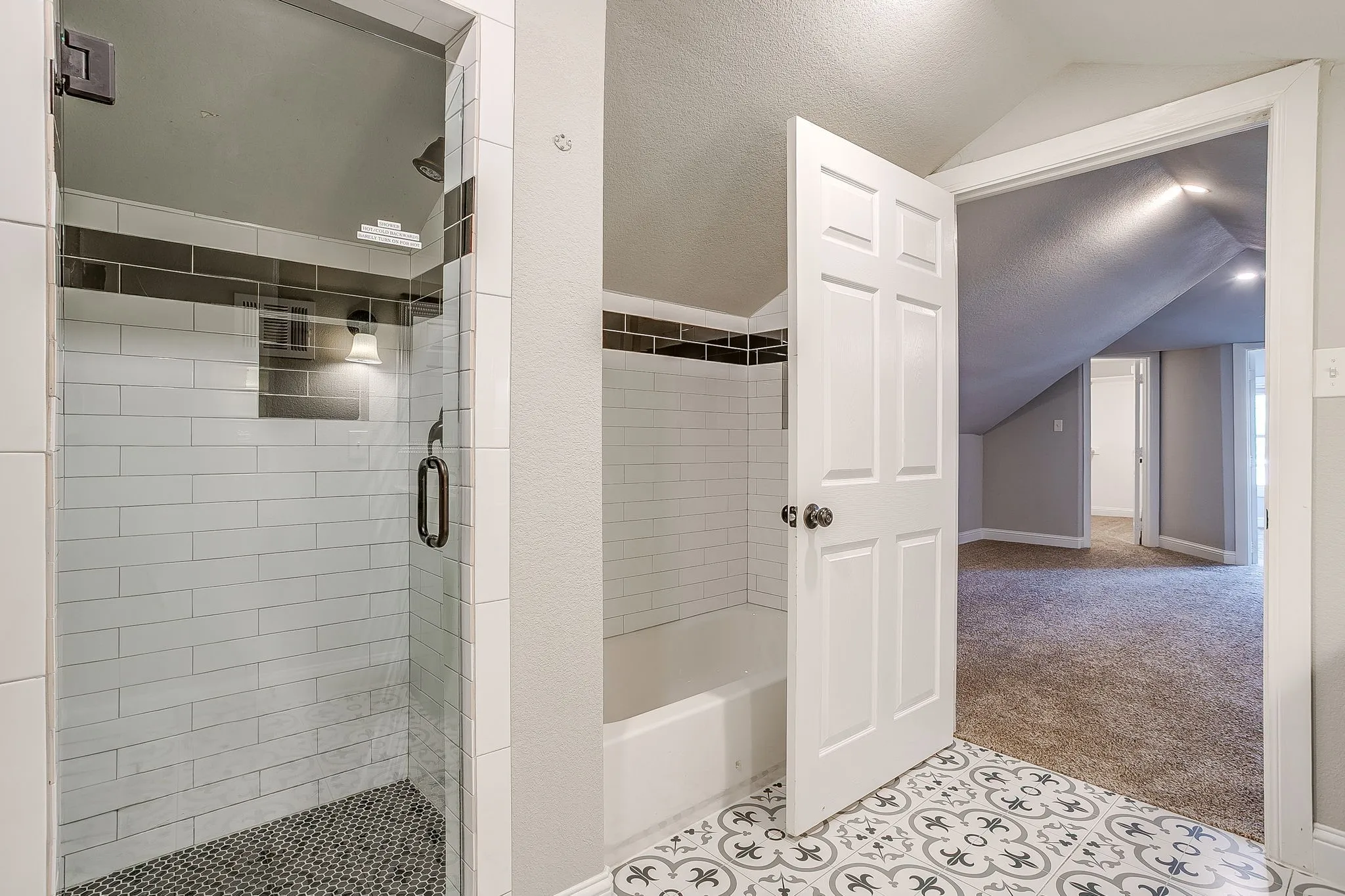 Glass-enclosed shower with subway tile surround and mosaic tile flooring