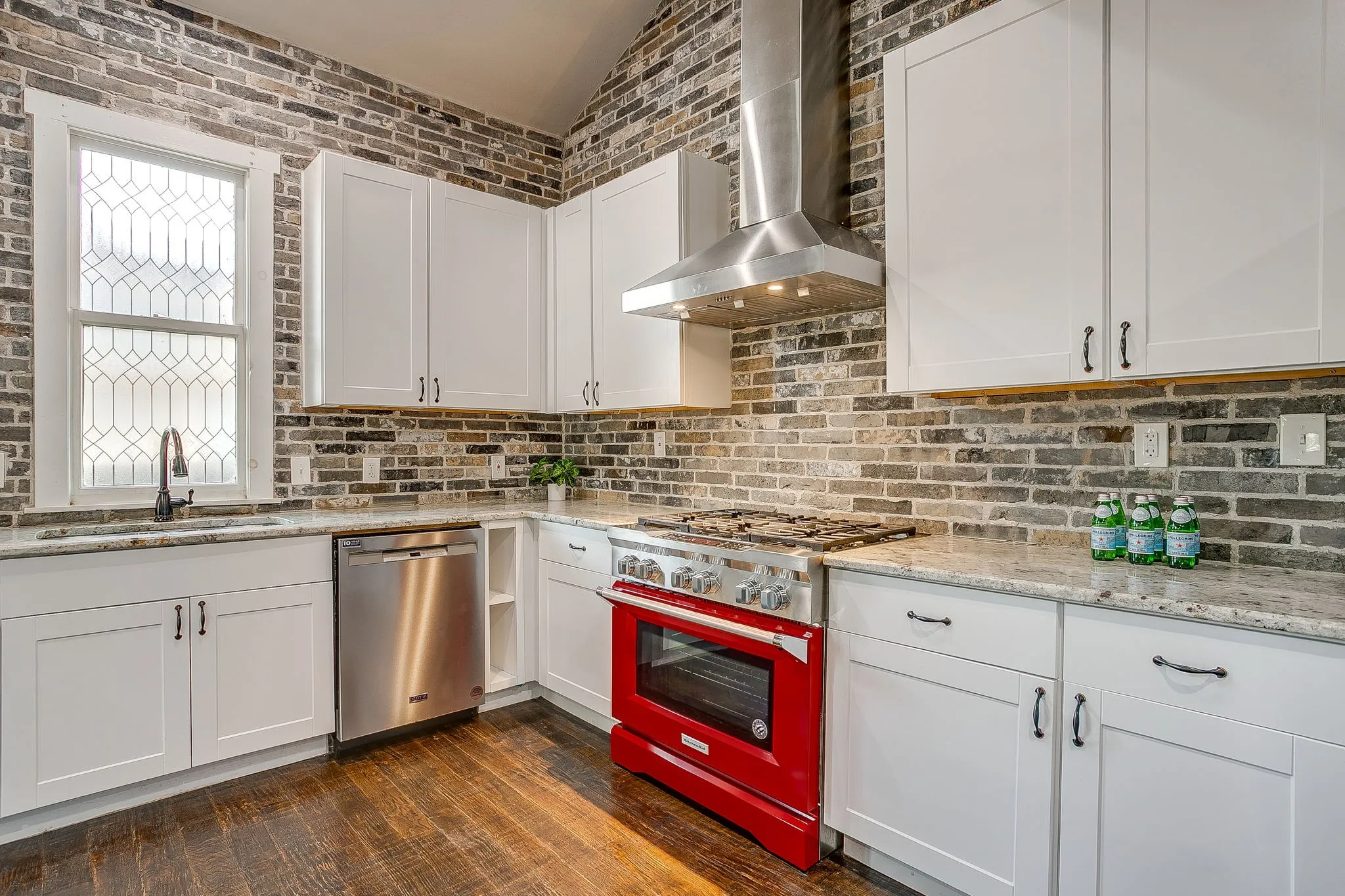 Kitchen featuring a red range oven, stainless steel dishwasher, white cabinetry, a decorative backsplash, and wood-finish flooring