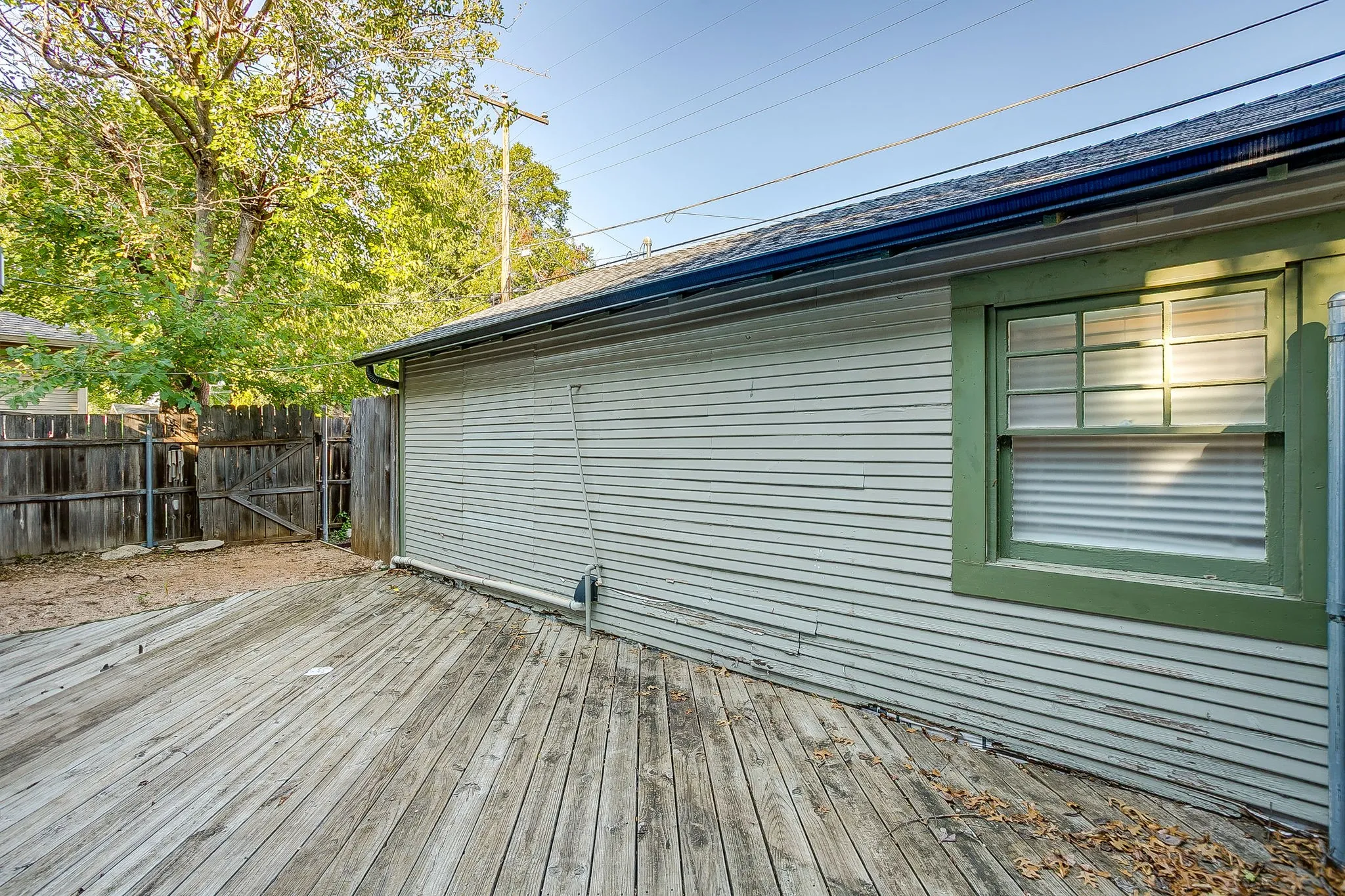 Hardwood deck, horizontal siding, green window trim, multi-pane window, and wood fence