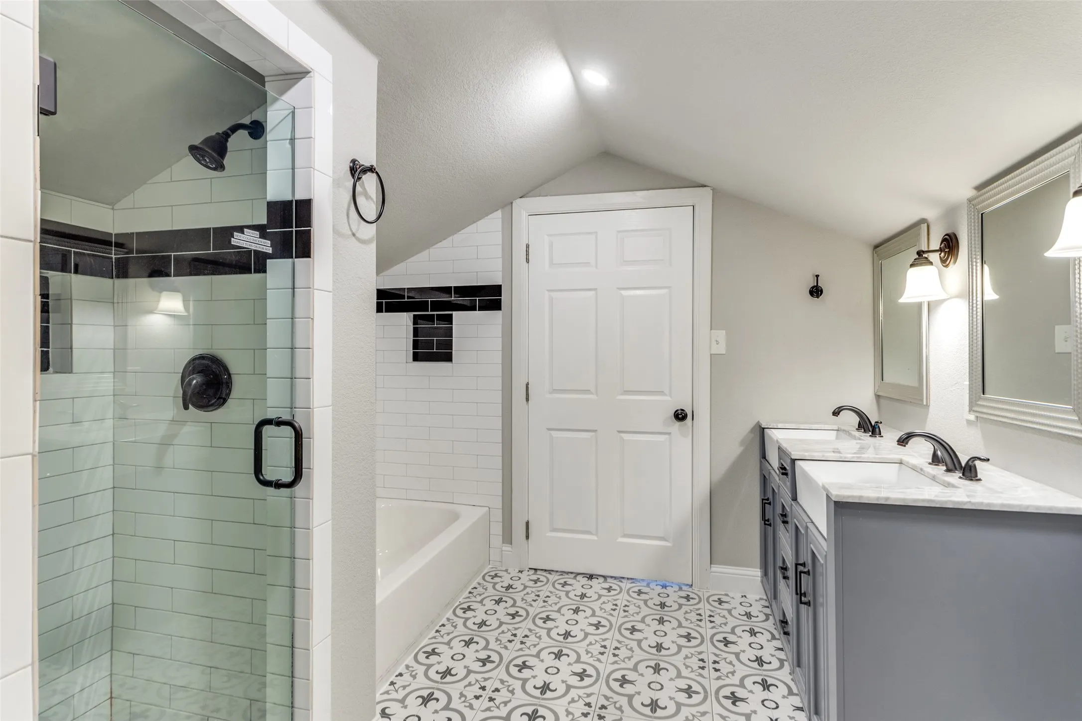 Glass-enclosed shower with subway tile surround, matte black fixtures, and a built-in niche