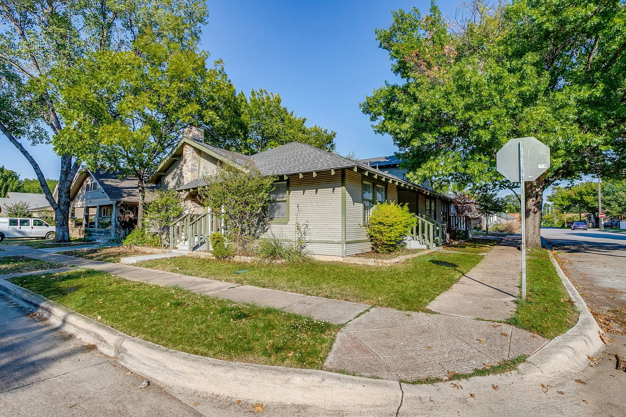 Craftsman-style residence with a stone chimney and a covered front porch featuring wooden railings