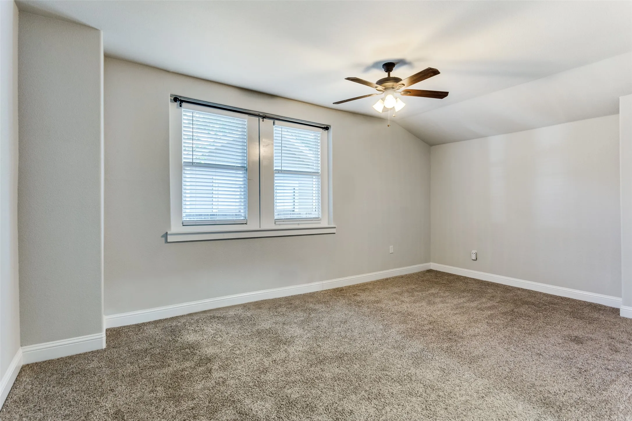Textured carpeting, neutral wall finishes, window with blinds, and a ceiling fan with integrated lighting