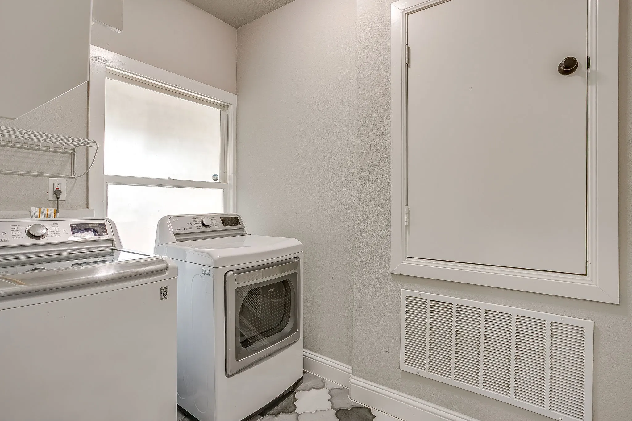 Laundry area featuring a window, patterned floor tile, and white baseboards
