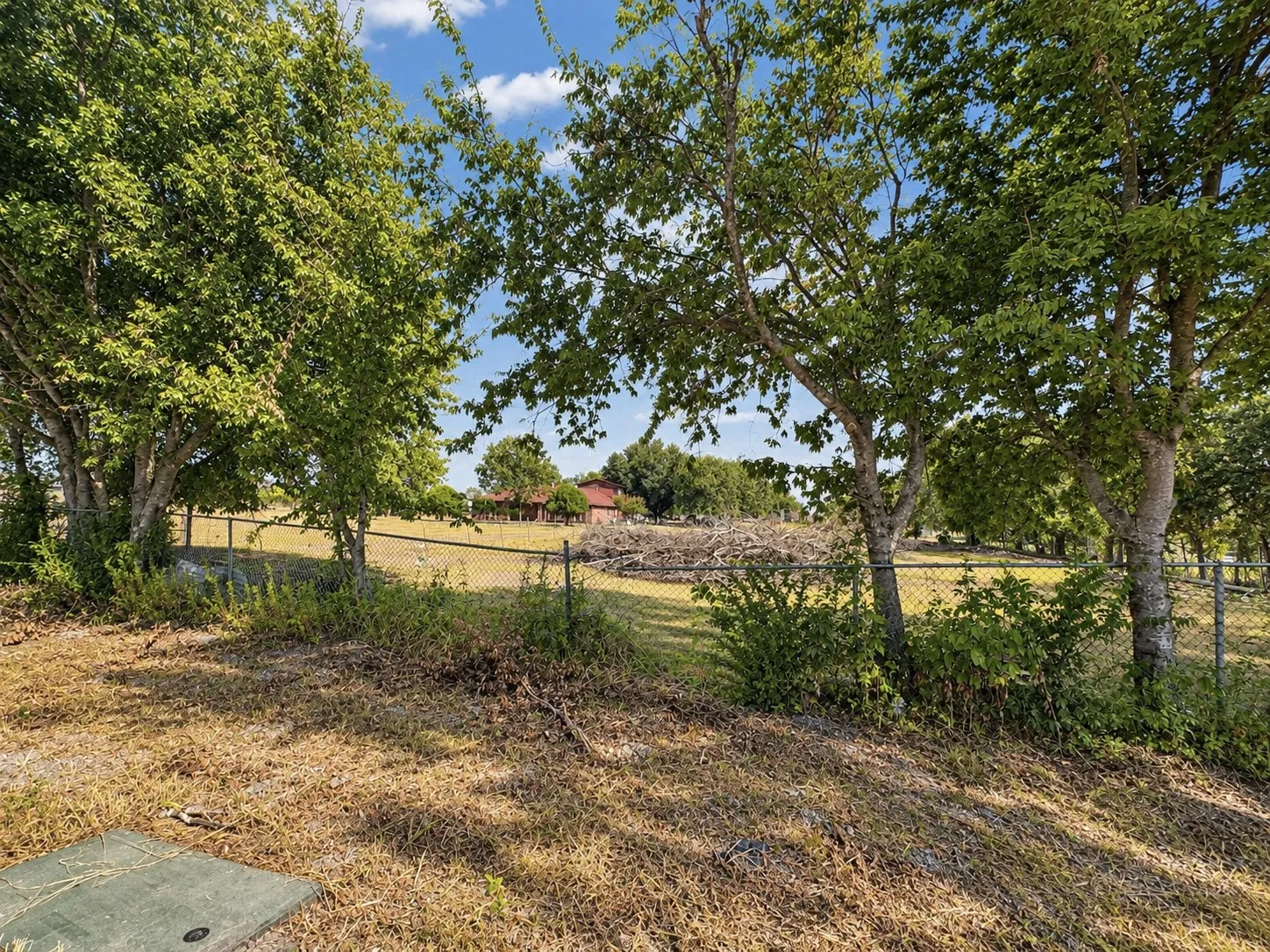 Expansive property featuring mature trees and a chain-link fence