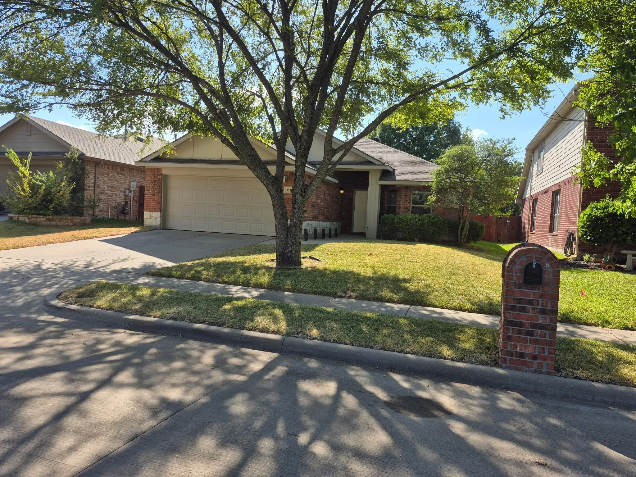 Brick exterior with partial siding, attached garage, and established front landscaping