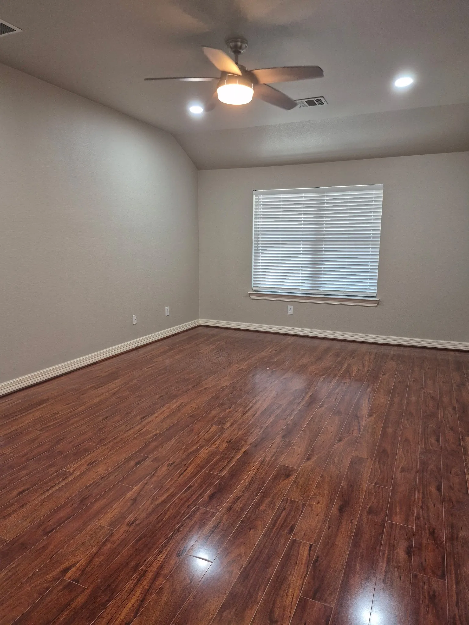 Expansive room with rich wood-finish flooring, recessed lighting, and a ceiling fan