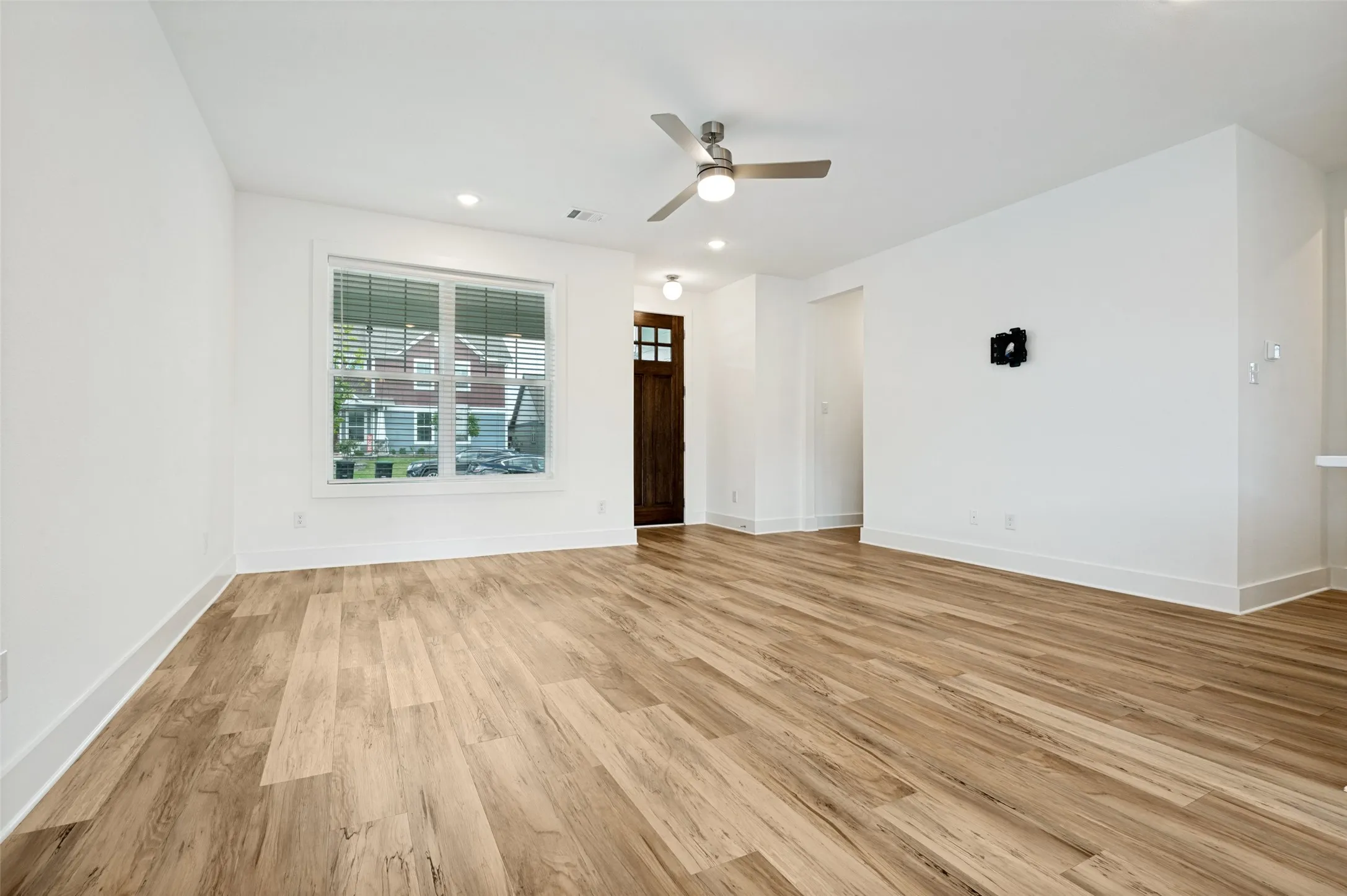 Wood-finish flooring, recessed lighting, ceiling fan, white trim, and a prominent window