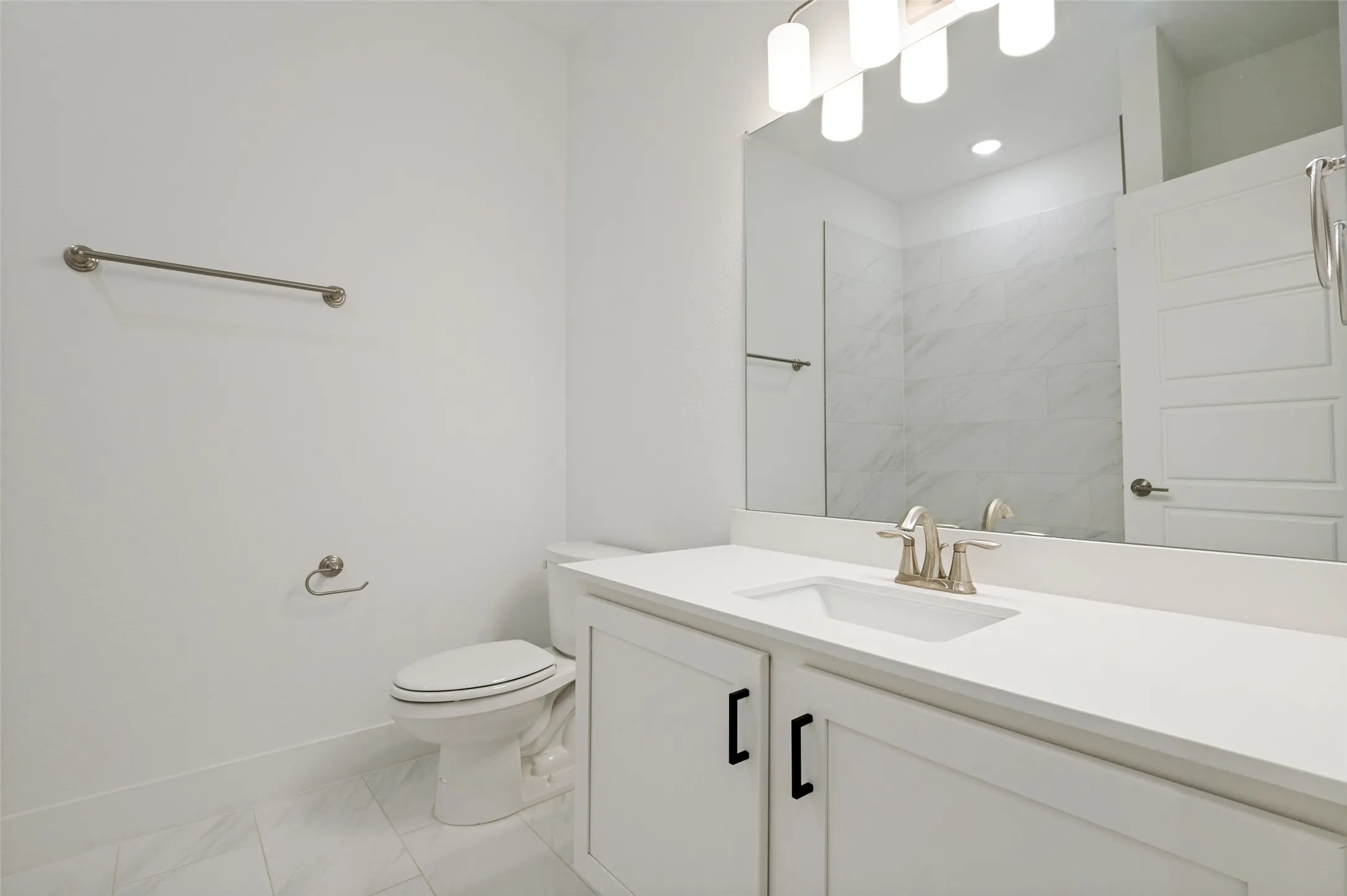 White vanity with black cabinet hardware, white countertop, undermount sink, and brushed nickel faucet