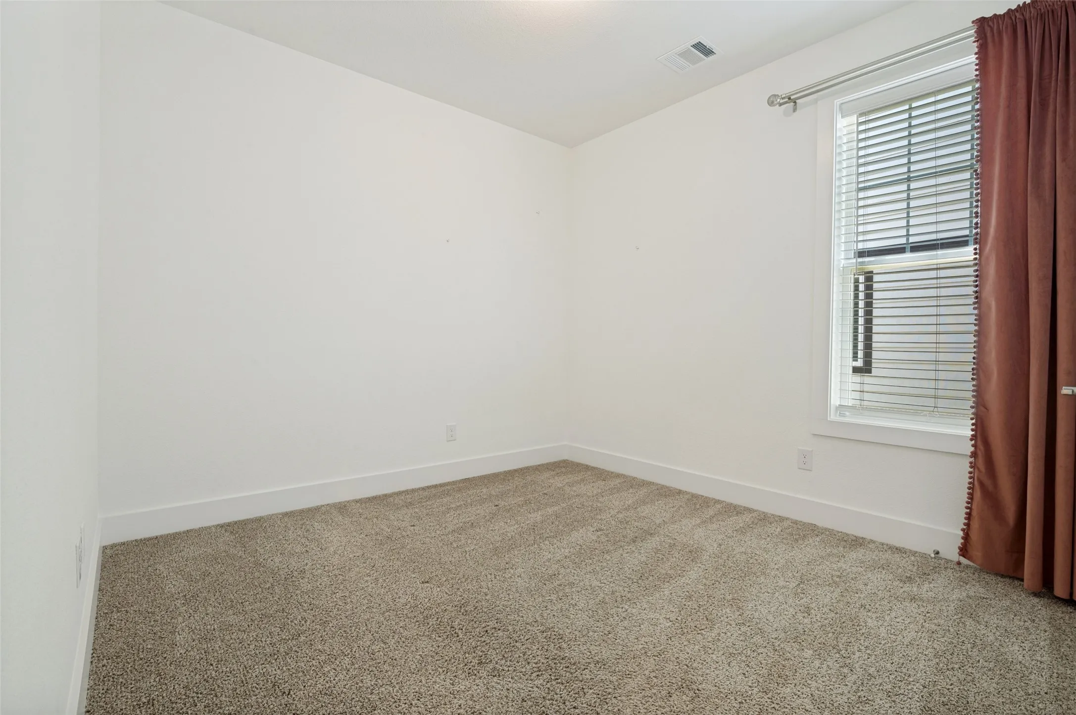 Carpeted room featuring a window with blinds