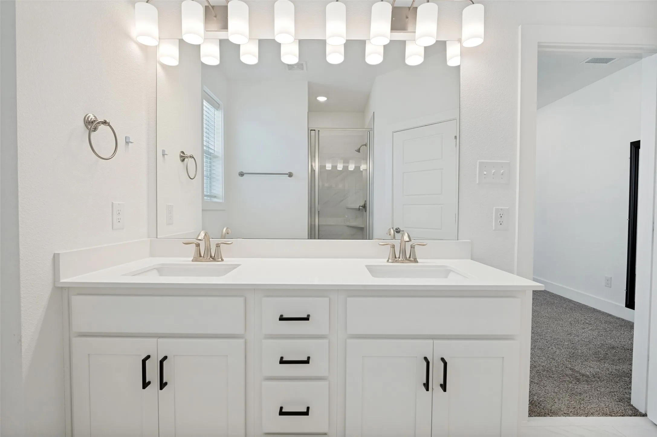 Dual vanity with white cabinetry, matte black hardware, integrated sinks, and brushed nickel faucets