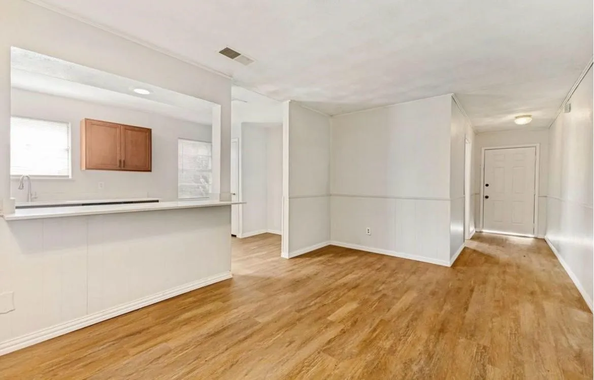 Wood-finish flooring, white paneling, and an open pass-through