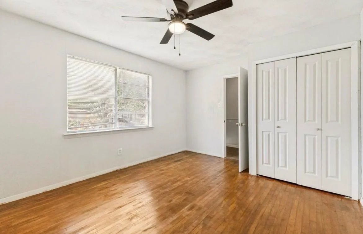 Wood-finish flooring, white walls, and a ceiling fan with integrated lighting