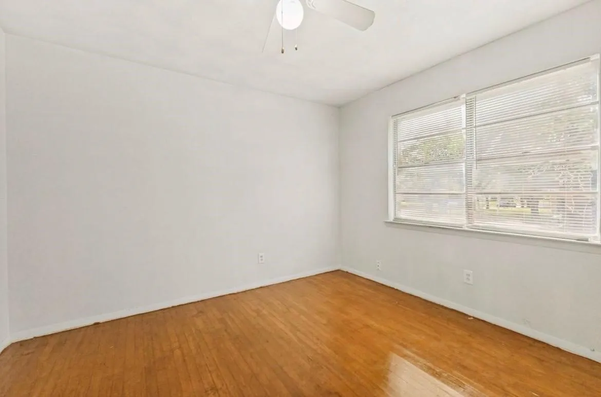 Wood-finish flooring, white walls, and a ceiling fan
