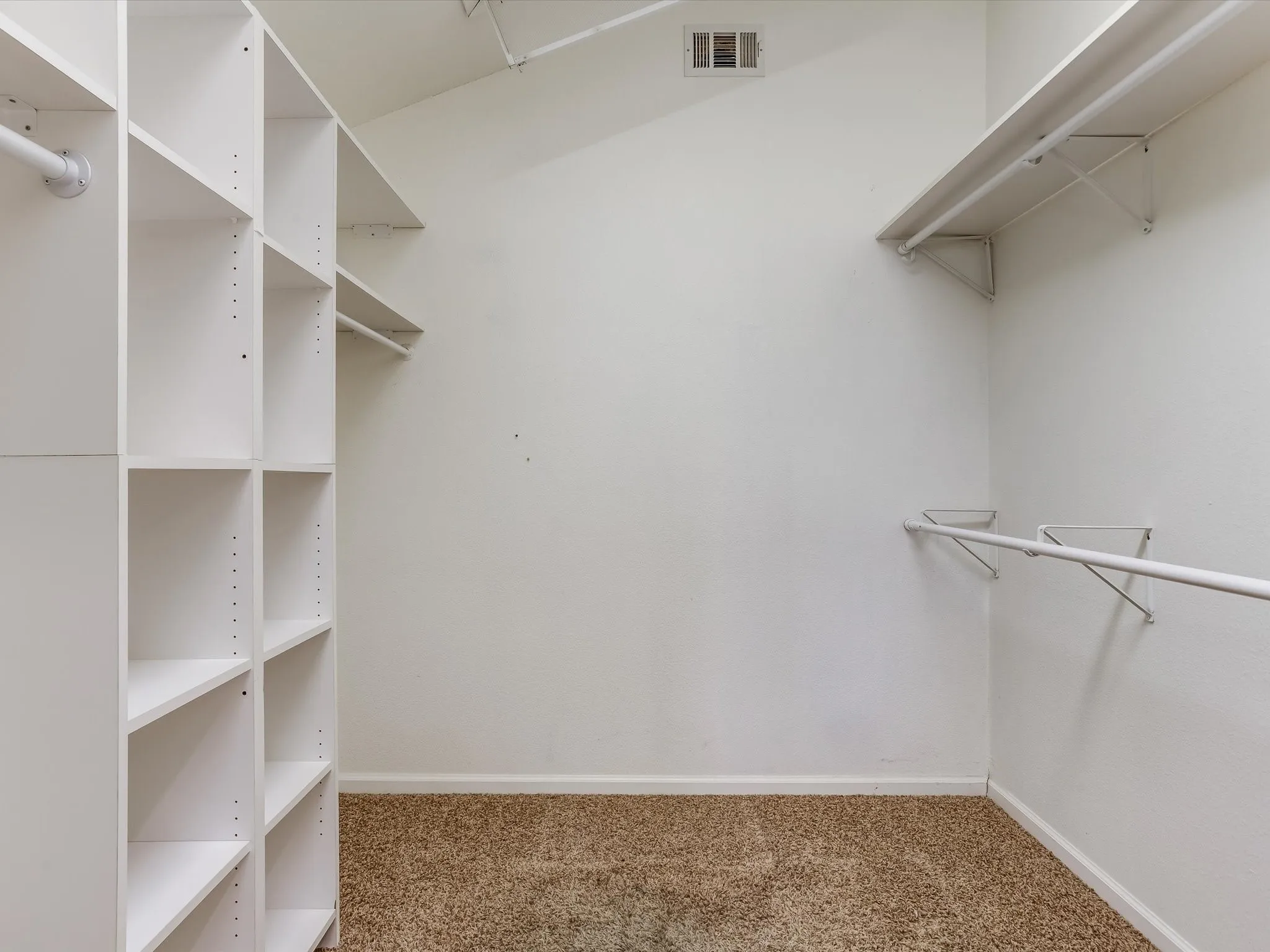 Walk-in closet featuring built-in shelving, white walls, and carpet flooring