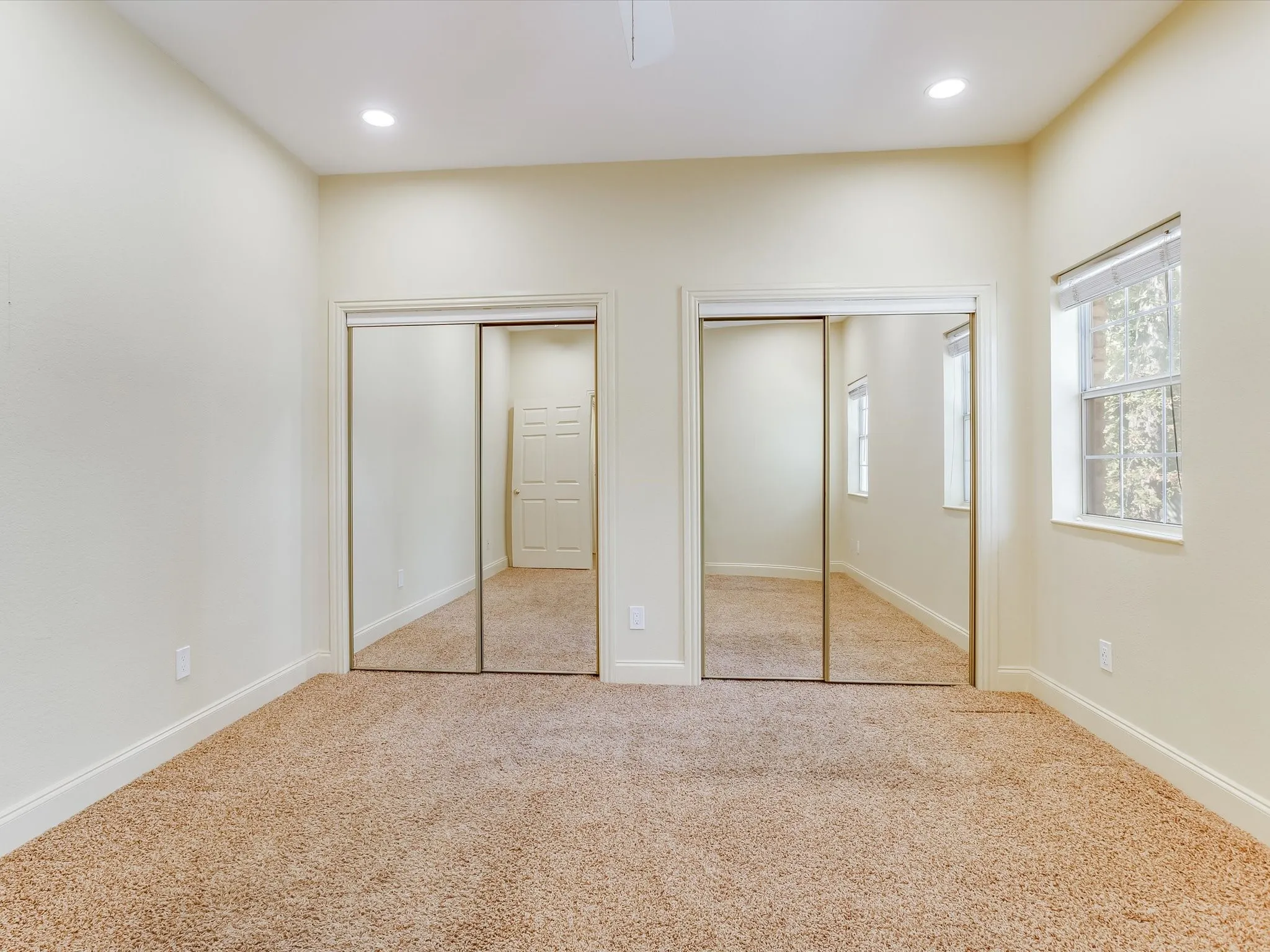 Bedroom 1 in the separate living quarters. Big bedroom! Recessed ceiling lighting, mirrored closet doors, dual sliding closets, window with natural light, and neutral wall tones