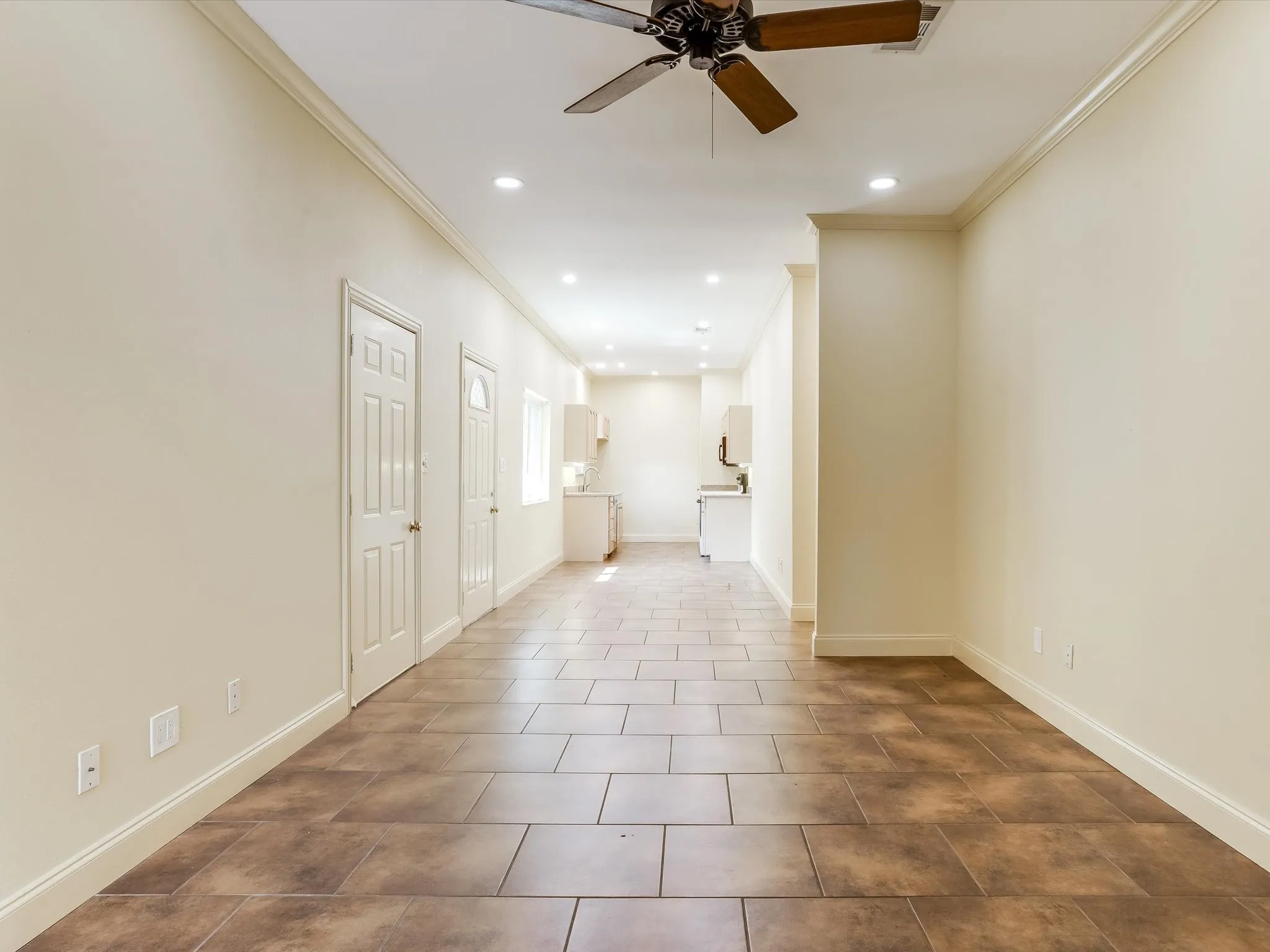 View when you walk in the door to the separate living quarters. Huge living space! Doors on the left are to the garage space and a door to outside. Recessed lighting, crown molding, ceiling fan, and tile flooring