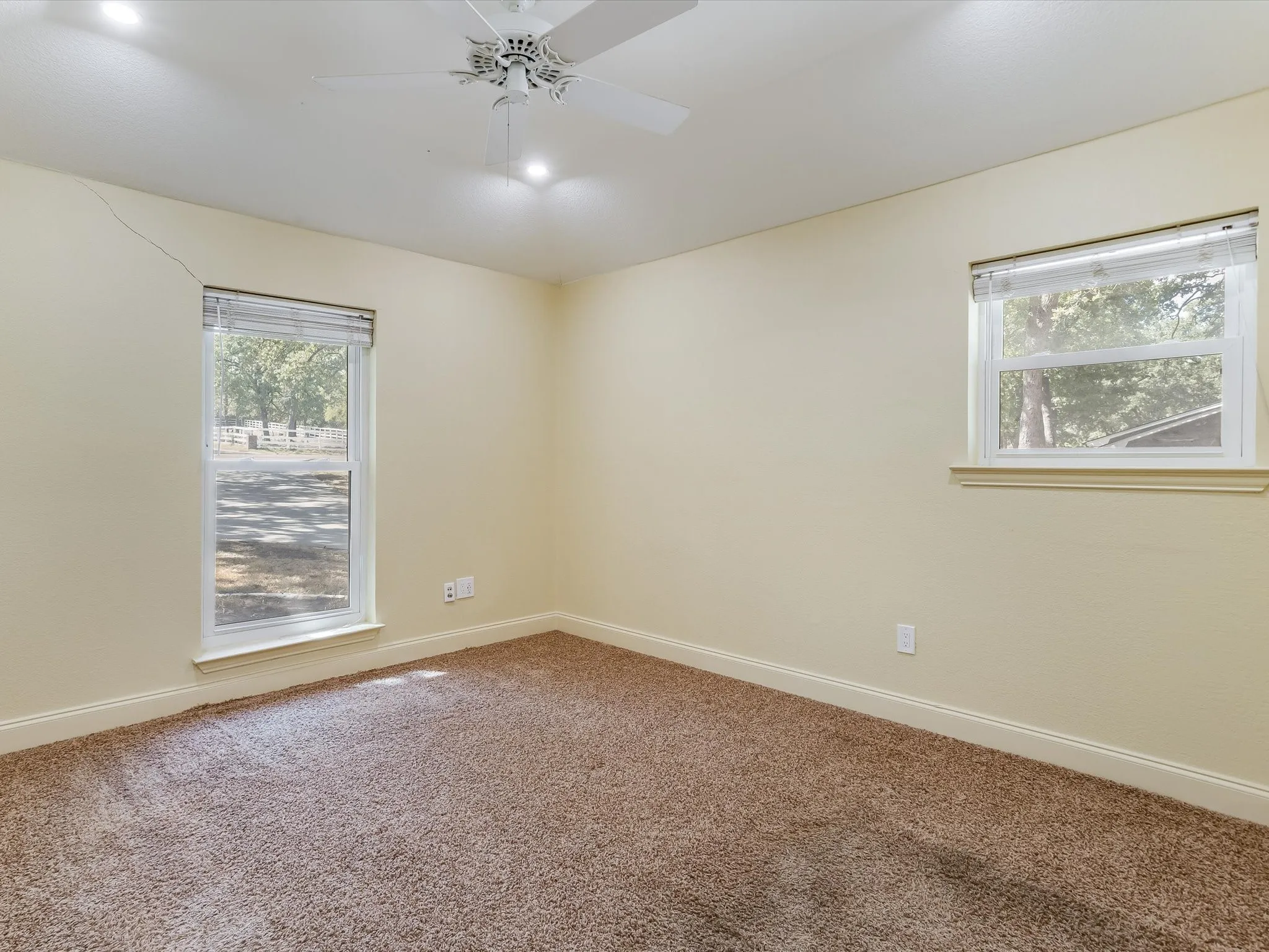 Recessed lighting, ceiling fan, two windows, and brown carpet