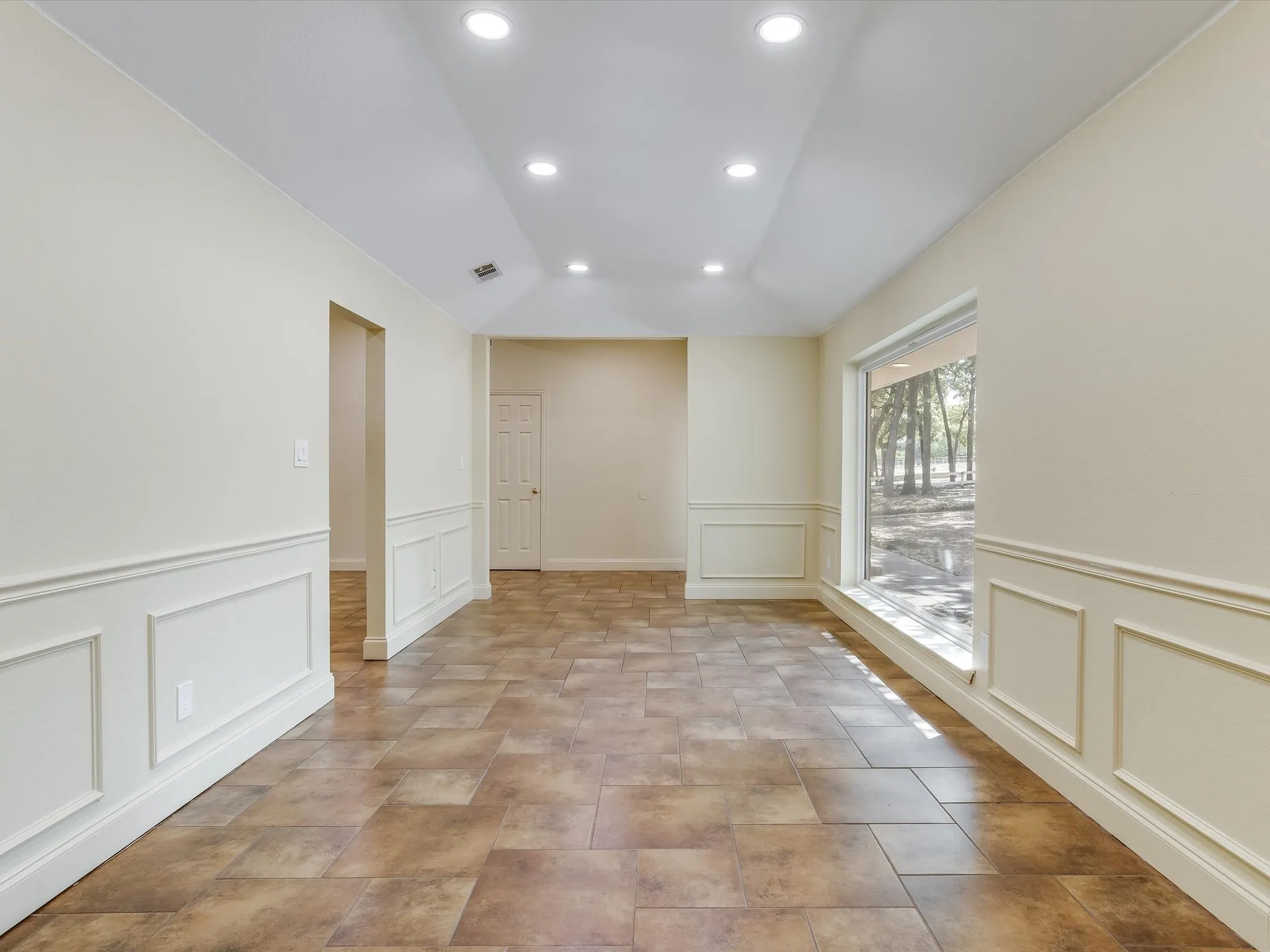 Recessed lighting illuminates the vaulted ceiling and neutral-toned walls