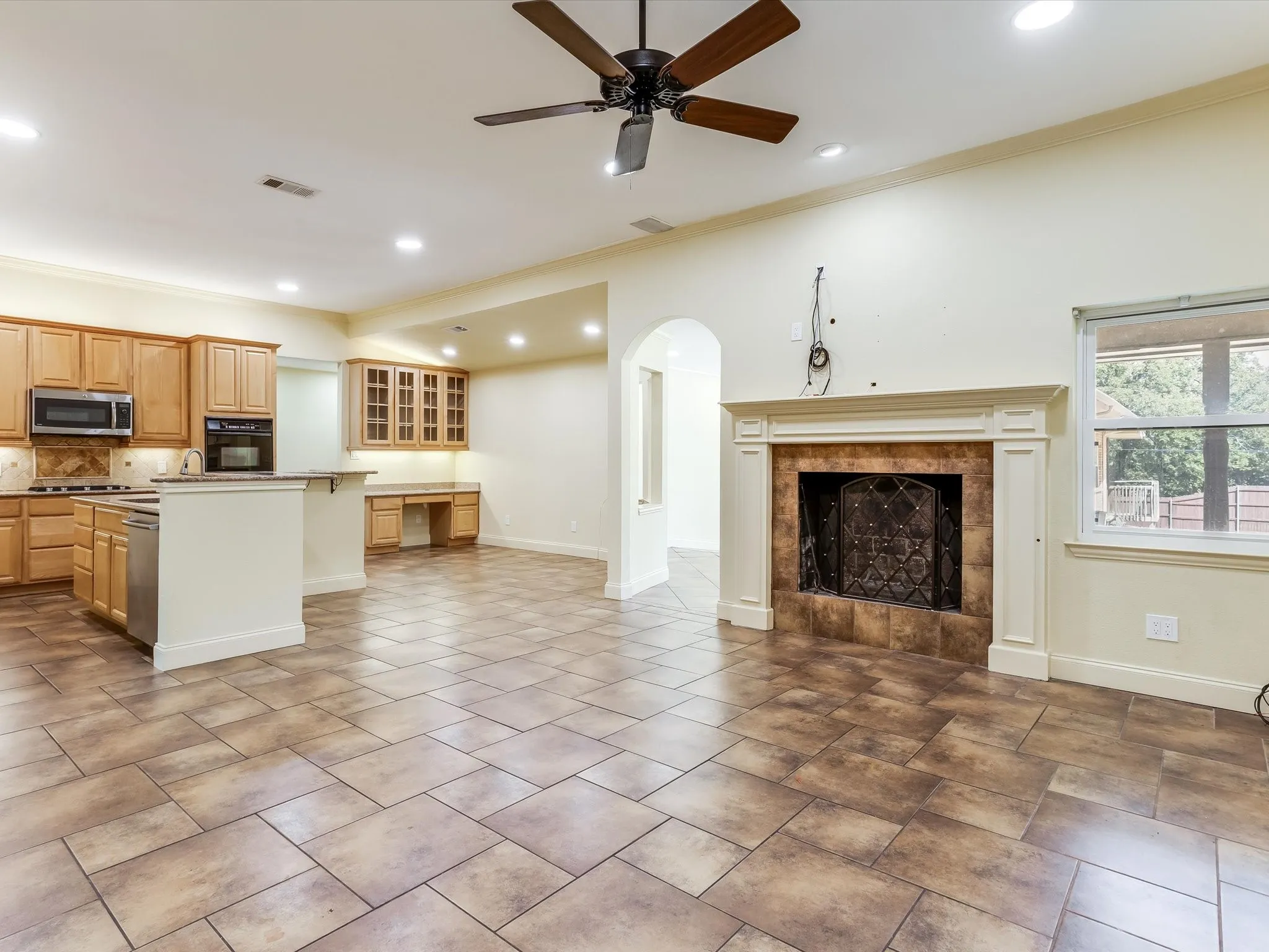 Recessed lighting, ceiling fan, fireplace with decorative mantel, tile flooring, and light wood cabinetry
