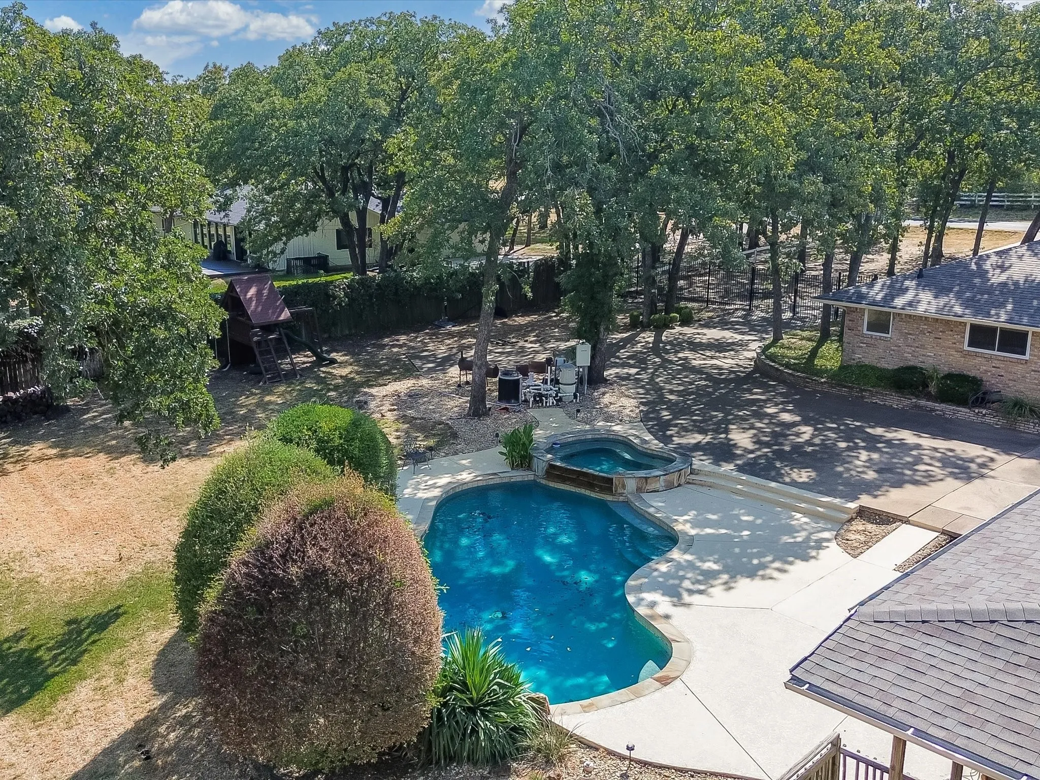 Freeform swimming pool with integrated spa and surrounding concrete decking