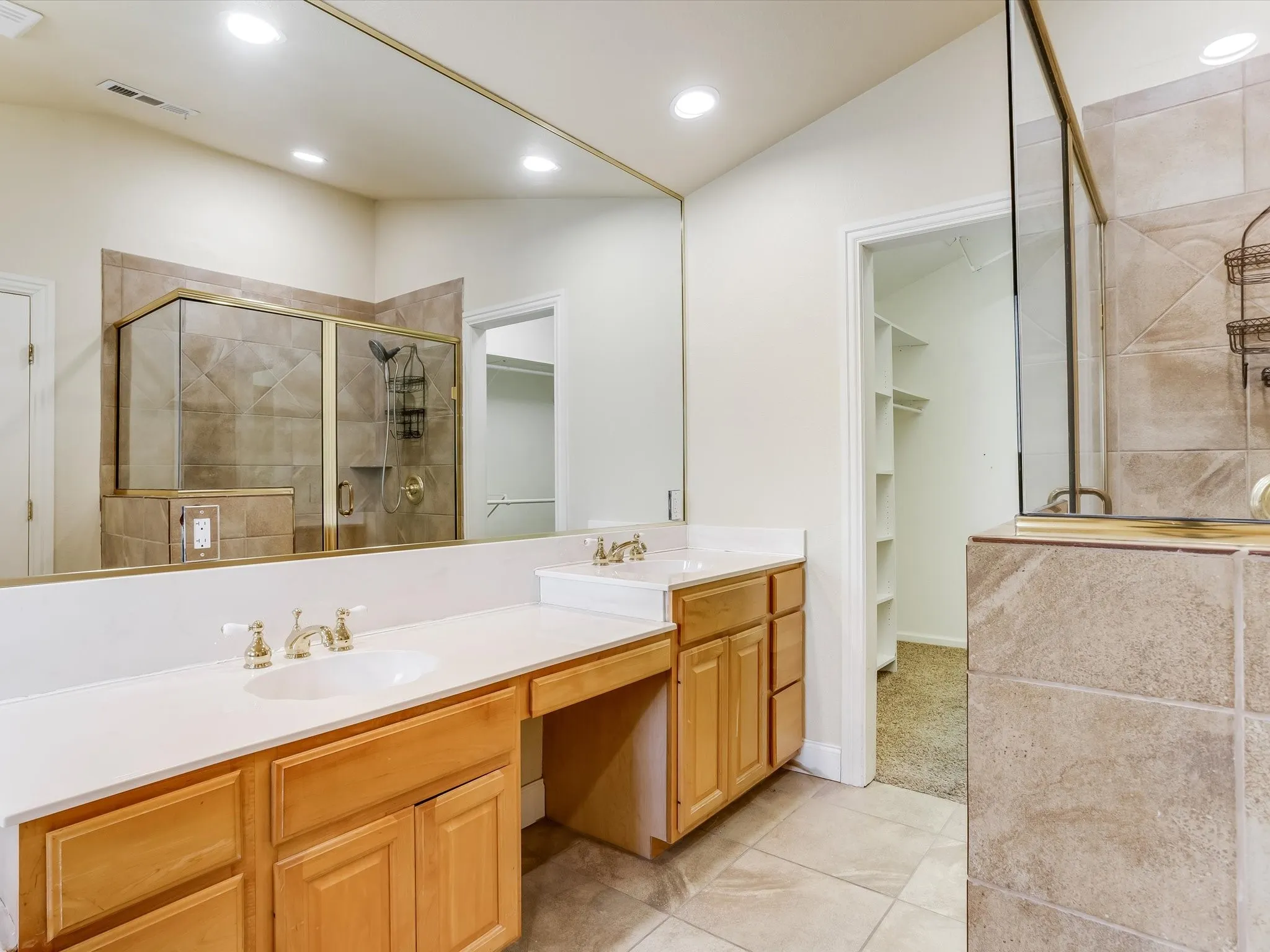 Primary bathroom. Dual vanity with white countertops, built-in cabinetry, and tile flooring