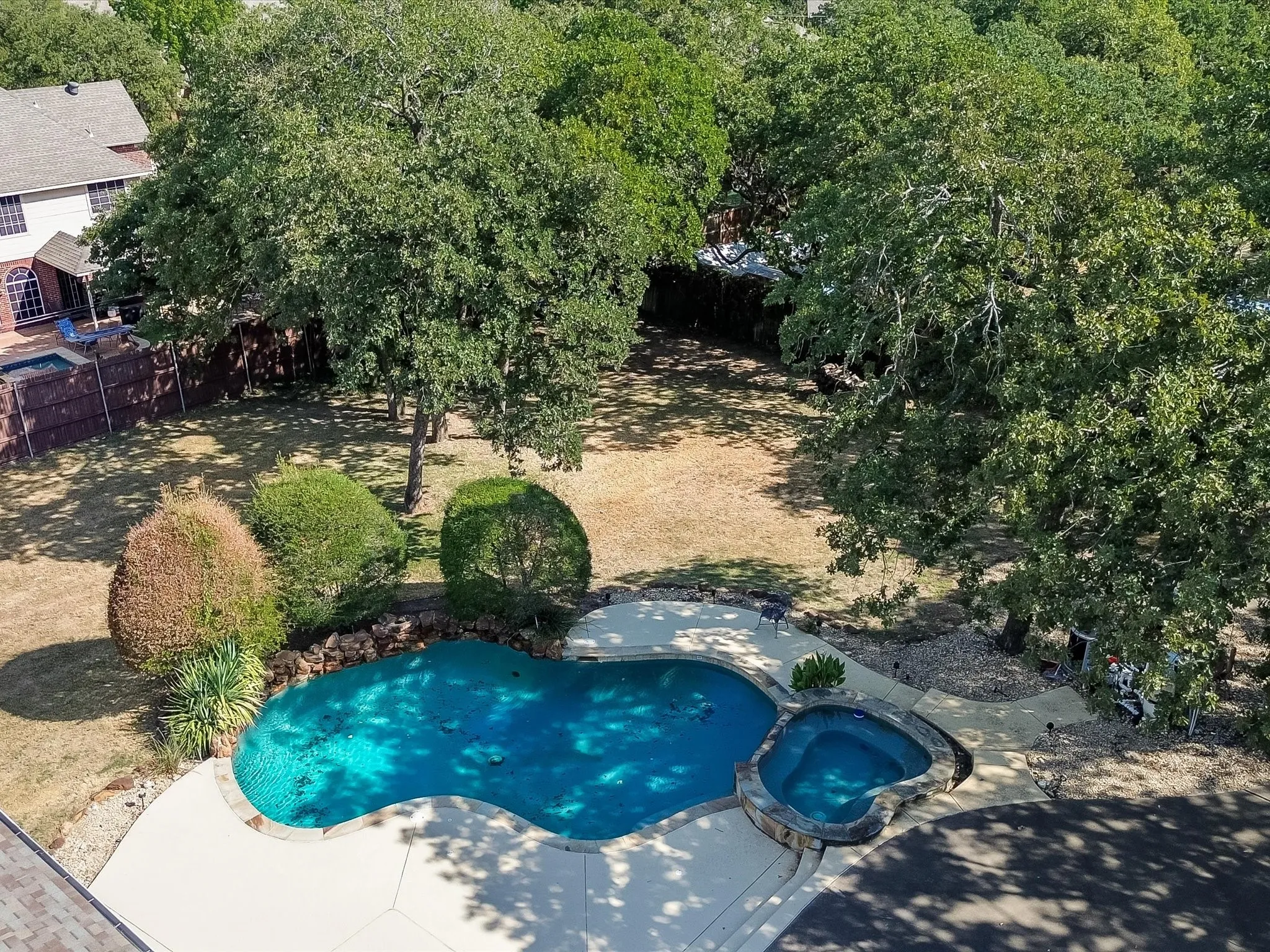 Freeform swimming pool with integrated spa and surrounding concrete decking