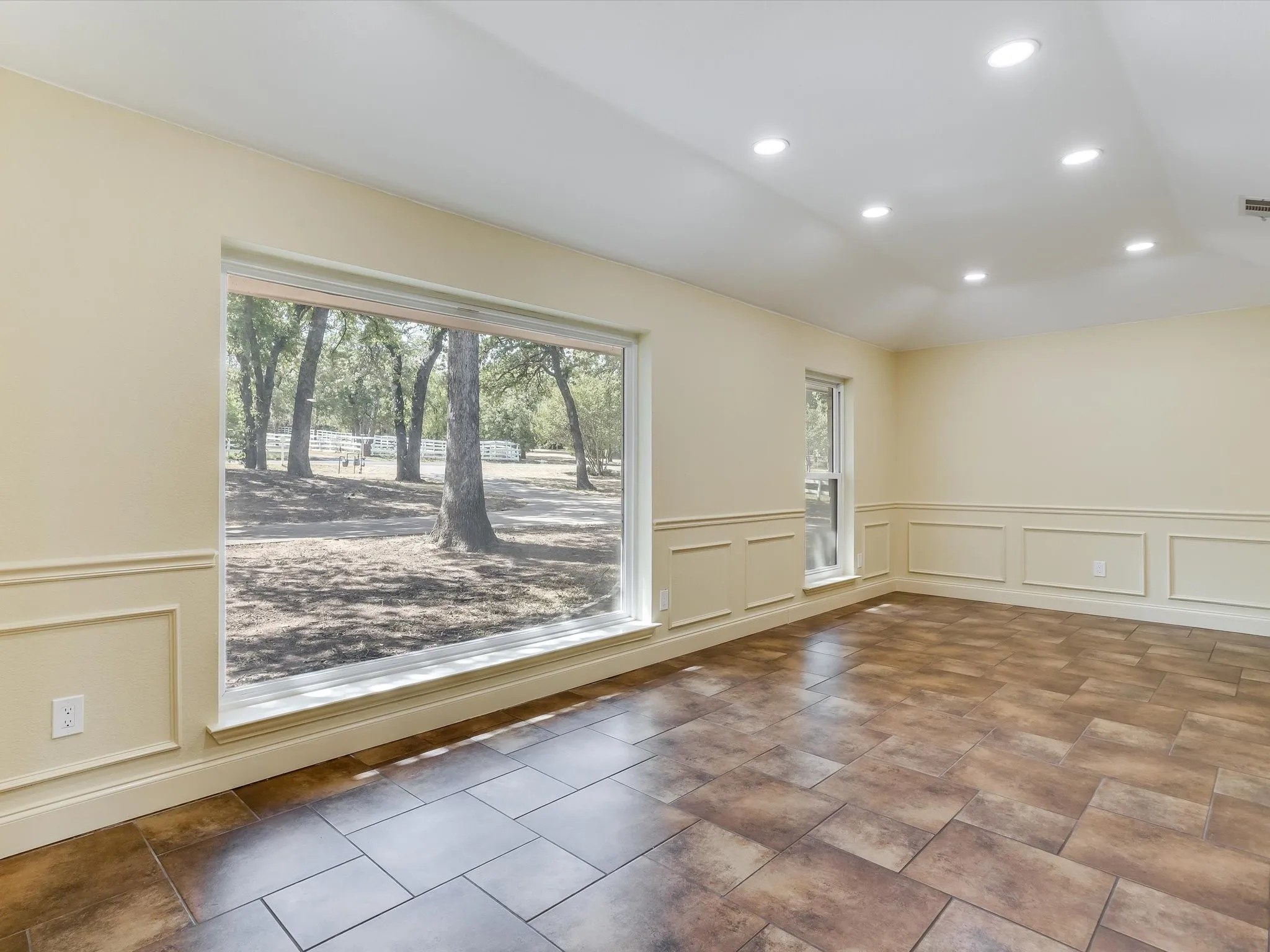 Massive formal dining room. Expansive window, recessed lighting, decorative wall paneling, and large format tile flooring