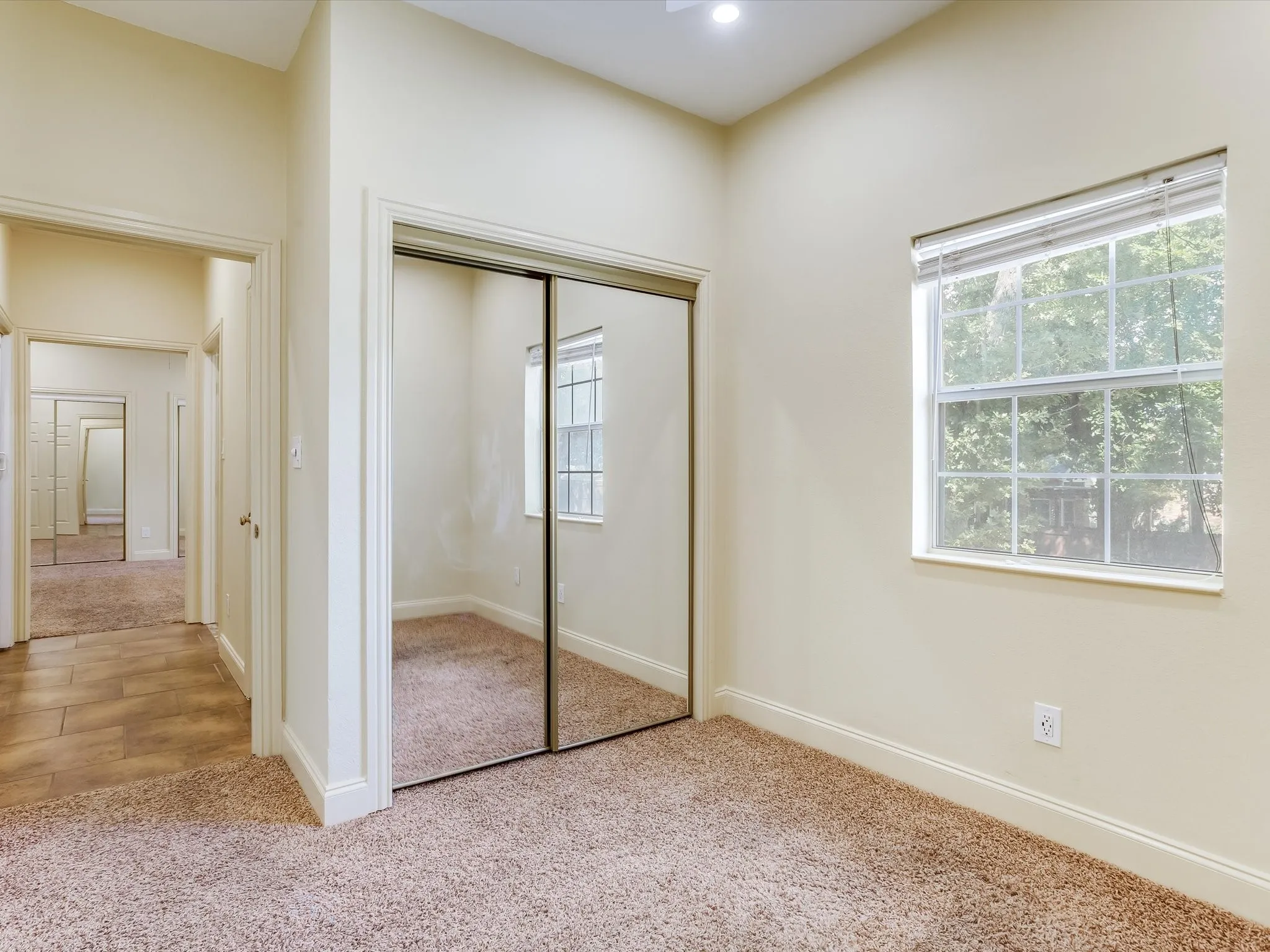 Bedroom 2 in the separate living quarters! Wall-to-wall carpeting with mirrored closet doors, a single window, and a recessed ceiling light