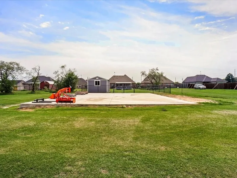 Expansive grass lawn with a concrete slab foundation and a detached storage shed