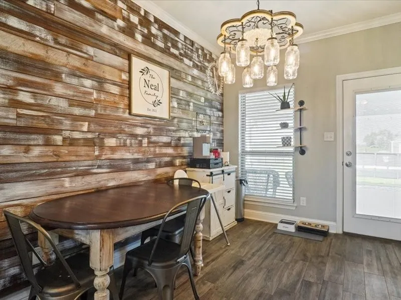 Wood-finish accent wall, wood-finish flooring, decorative chandelier, transom window, and exterior door