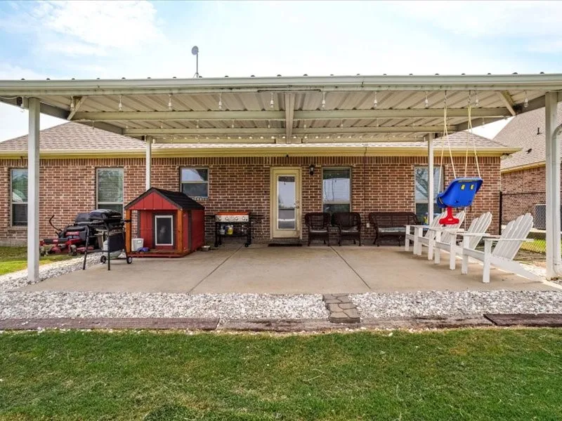 Covered patio area with concrete surfacing, brick exterior, and a gravel border