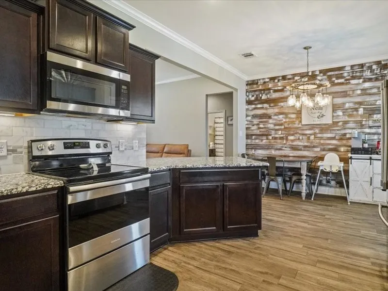 Kitchen featuring dark wood cabinetry, stainless steel appliances, granite countertops, and a subway tile backsplash