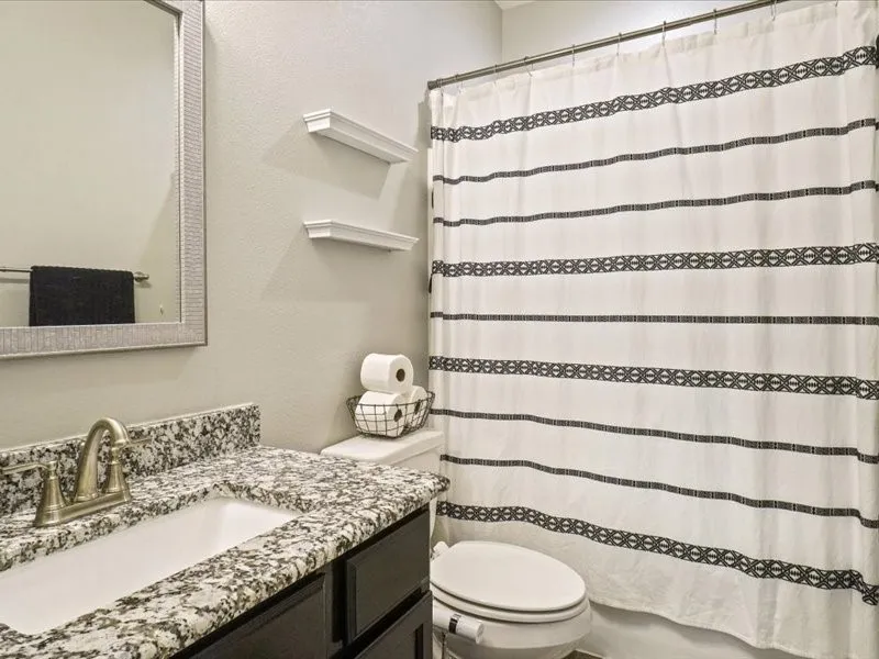 Bathroom featuring a vanity with granite-style countertop, undermount sink, and brushed nickel faucet
