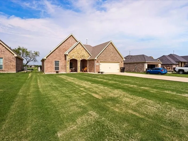 Brick exterior with stone accents, covered entry, attached garage, and a concrete driveway
