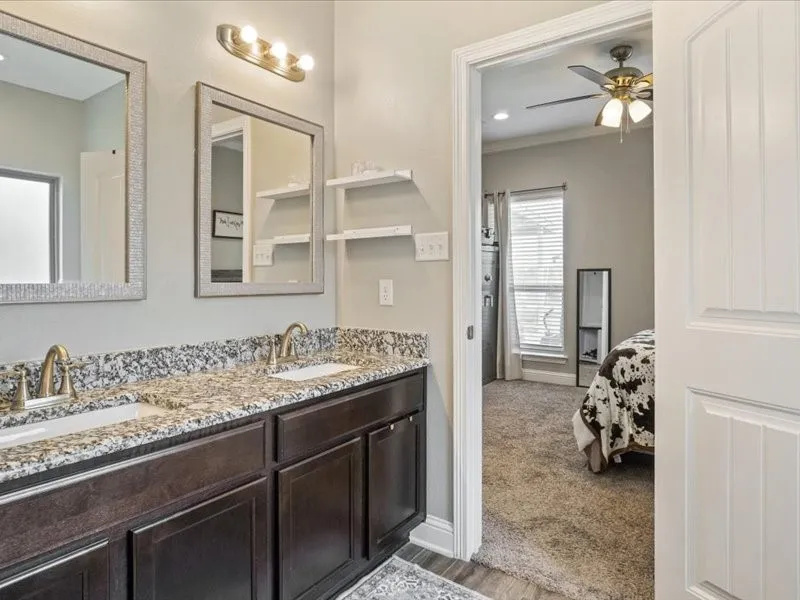 Double vanity with stone-finish countertop, two undermount sinks, and wall-mounted light fixture