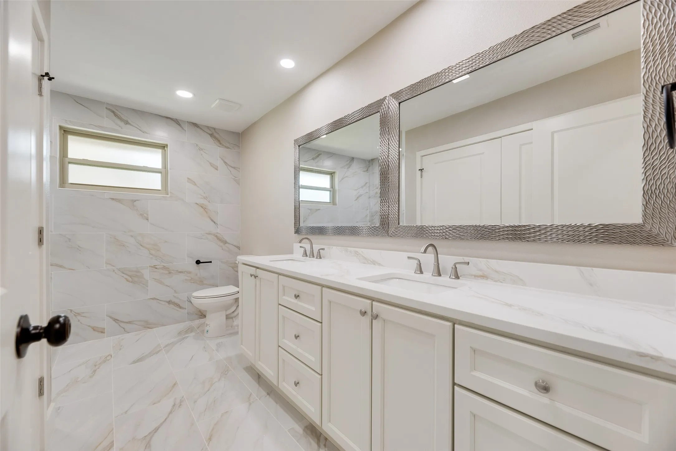 Full bath with light marble finish flooring, double vanity, plenty of natural light, and recessed lighting
