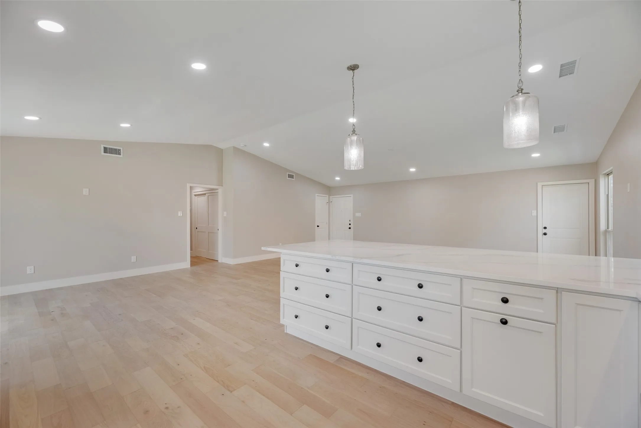 Kitchen featuring open floor plan, white cabinets, hanging light fixtures, quarts countertops, and recessed lighting