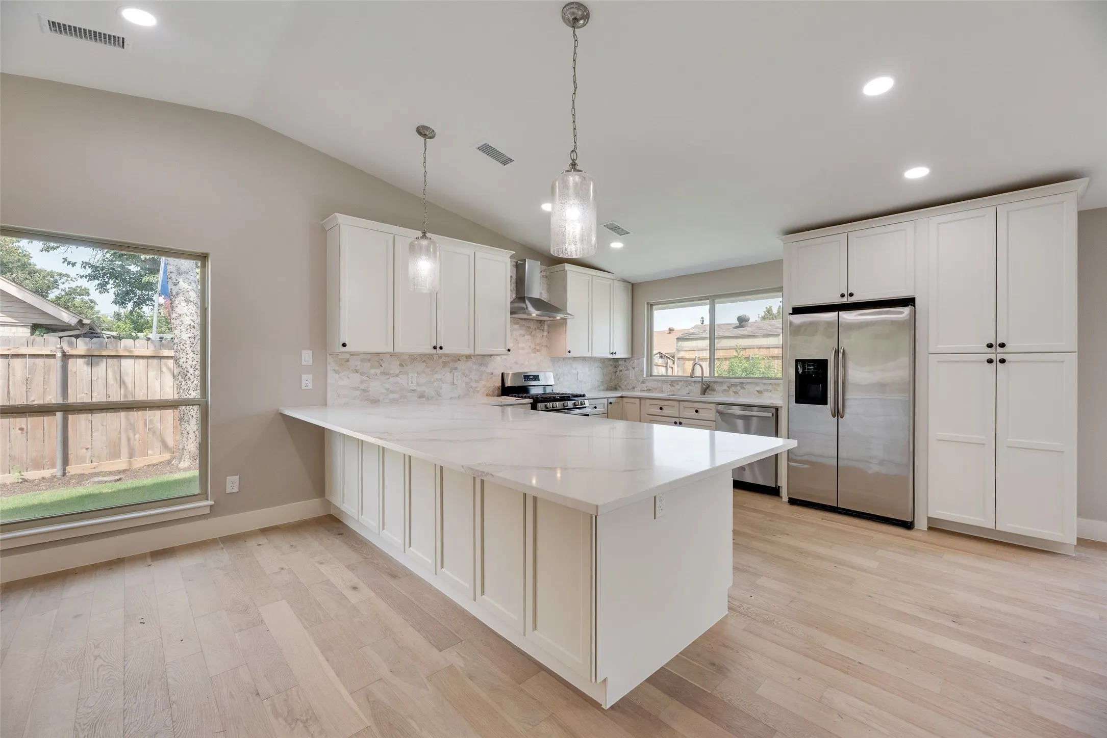 Kitchen featuring stainless steel appliances, a peninsula, recessed lighting, backsplash, and pendant lighting