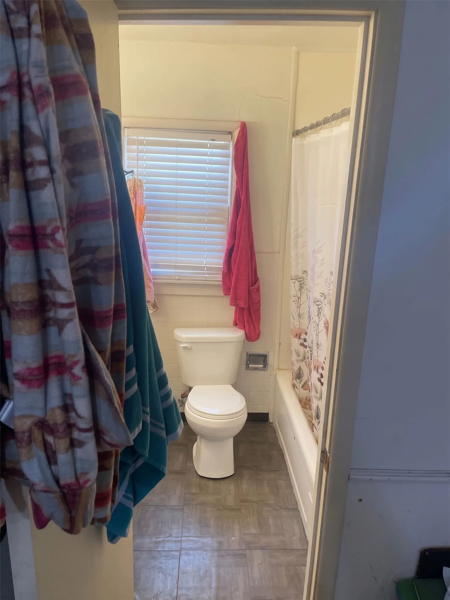 Full bathroom featuring a single vanity sink, toilet, window light, and tub/shower combination.