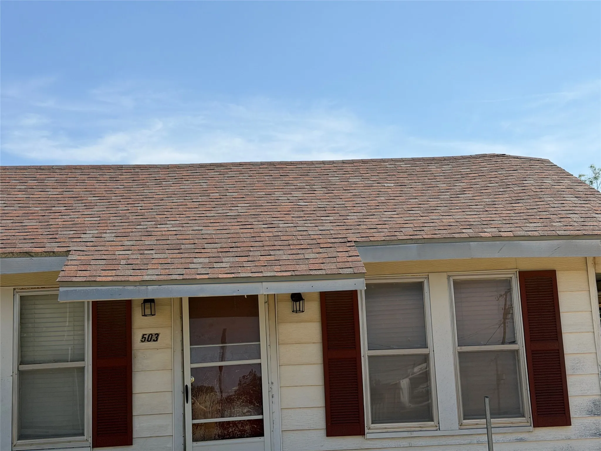 Close-up view of the front porch area displaying double windows with shutters and front entry door.