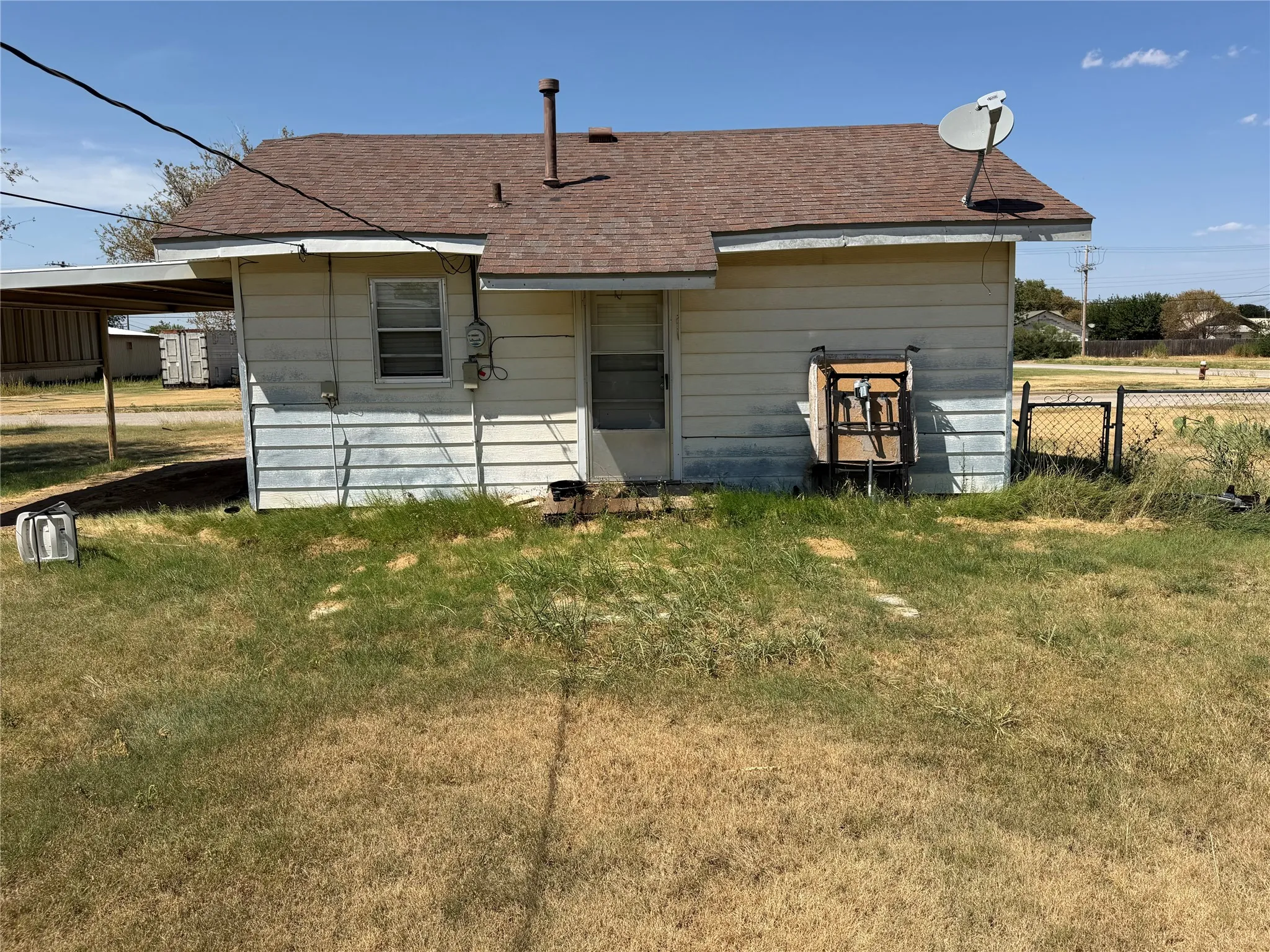 Wide view of the back yard area and rear profile of the residence under open skies.