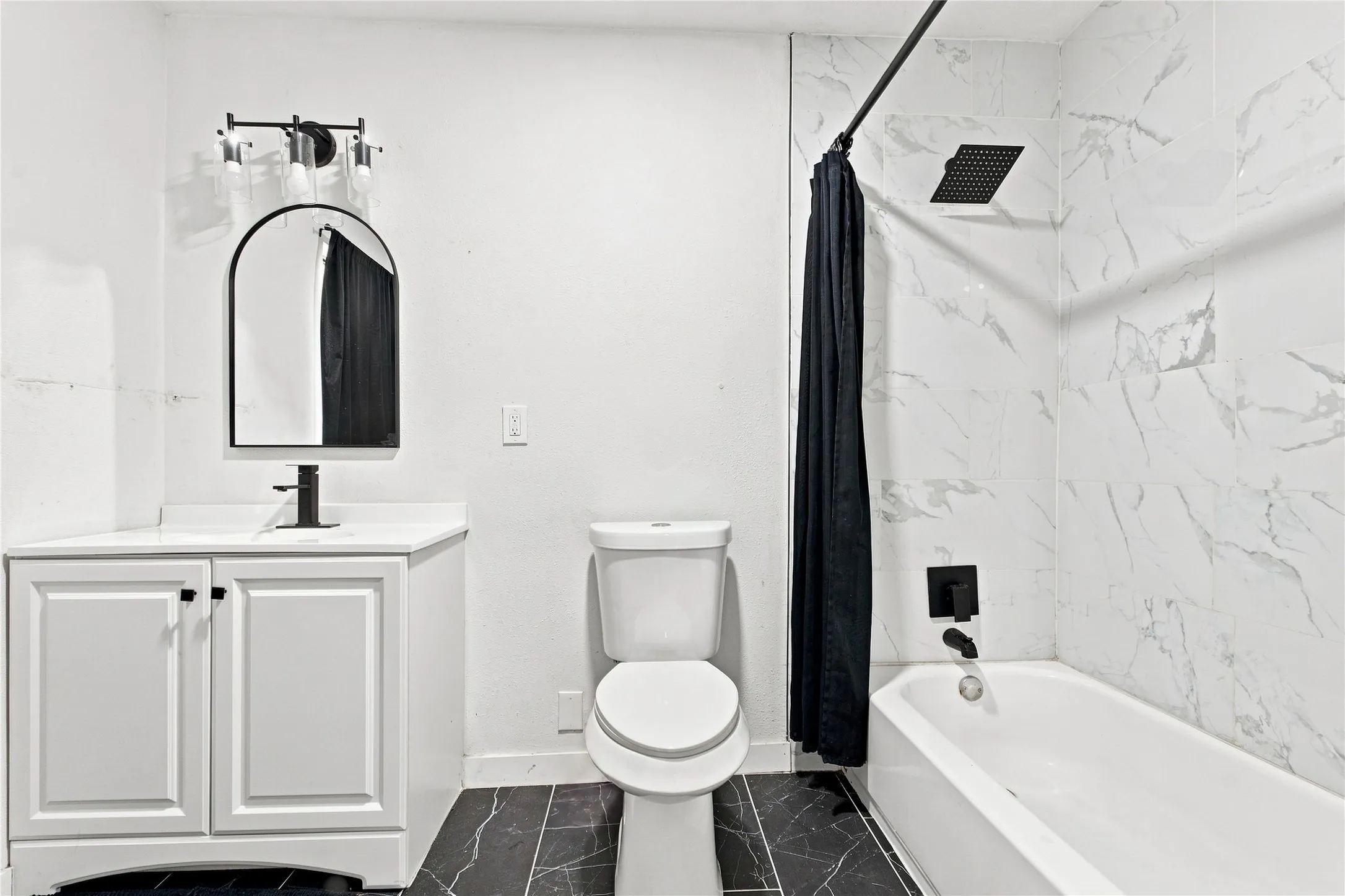 Bathroom featuring a white vanity with built-in storage, a white toilet, and a bathtub with a shower