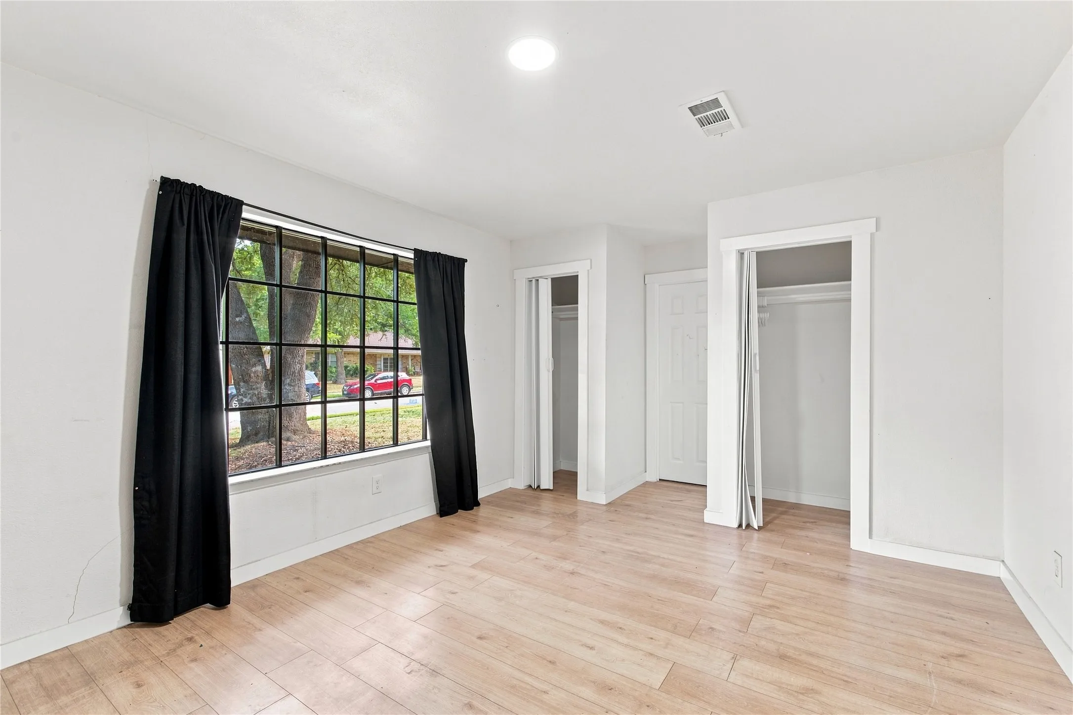 Wood-finish flooring, recessed ceiling lighting, and a large grid-pattern window